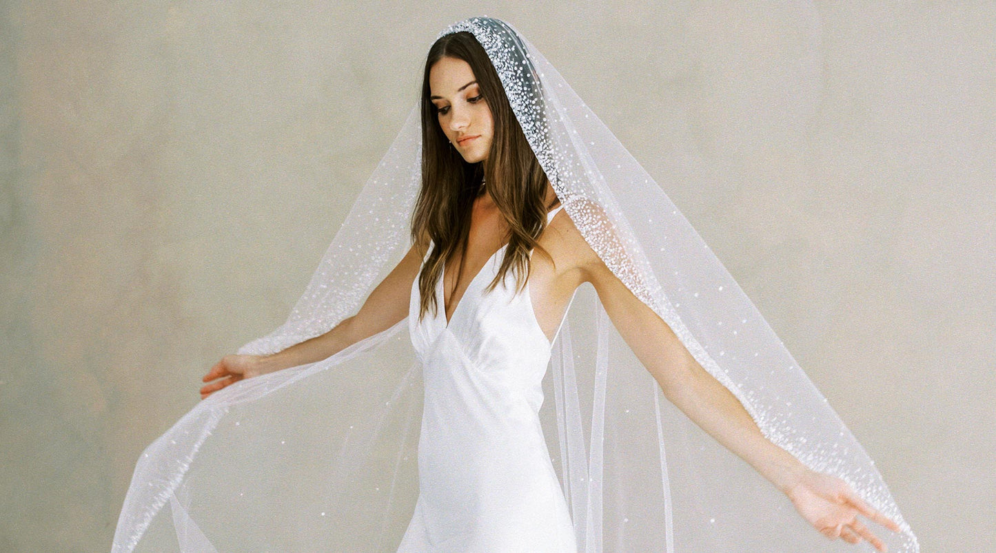 A bride wearing a white minimalist gown and a pearl and sequin wedding veil by Madame Tulle bridal