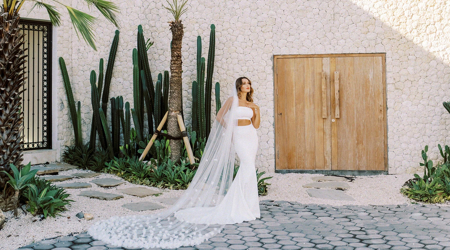 A bride wearing a white modern gown with a long floral wedding veil