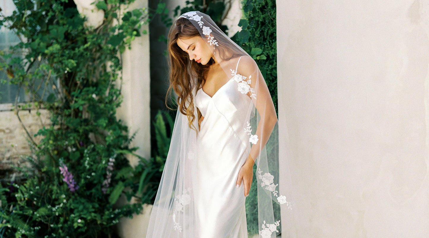 A bride wearing a plain white gown and a beatiful romantic veil with lace appliques