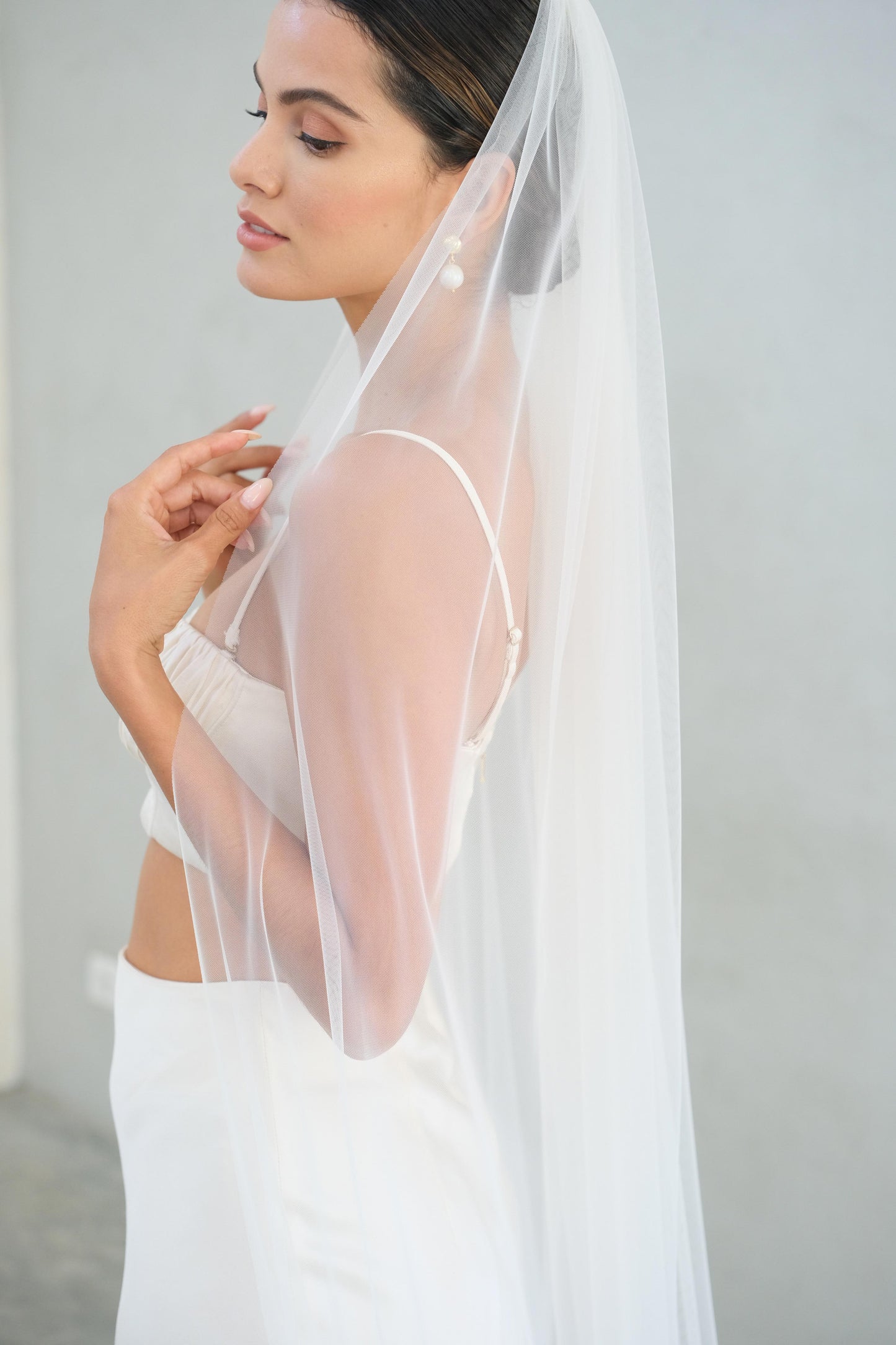 Half length side view of bride wearing long, soft tulle one-tier veil