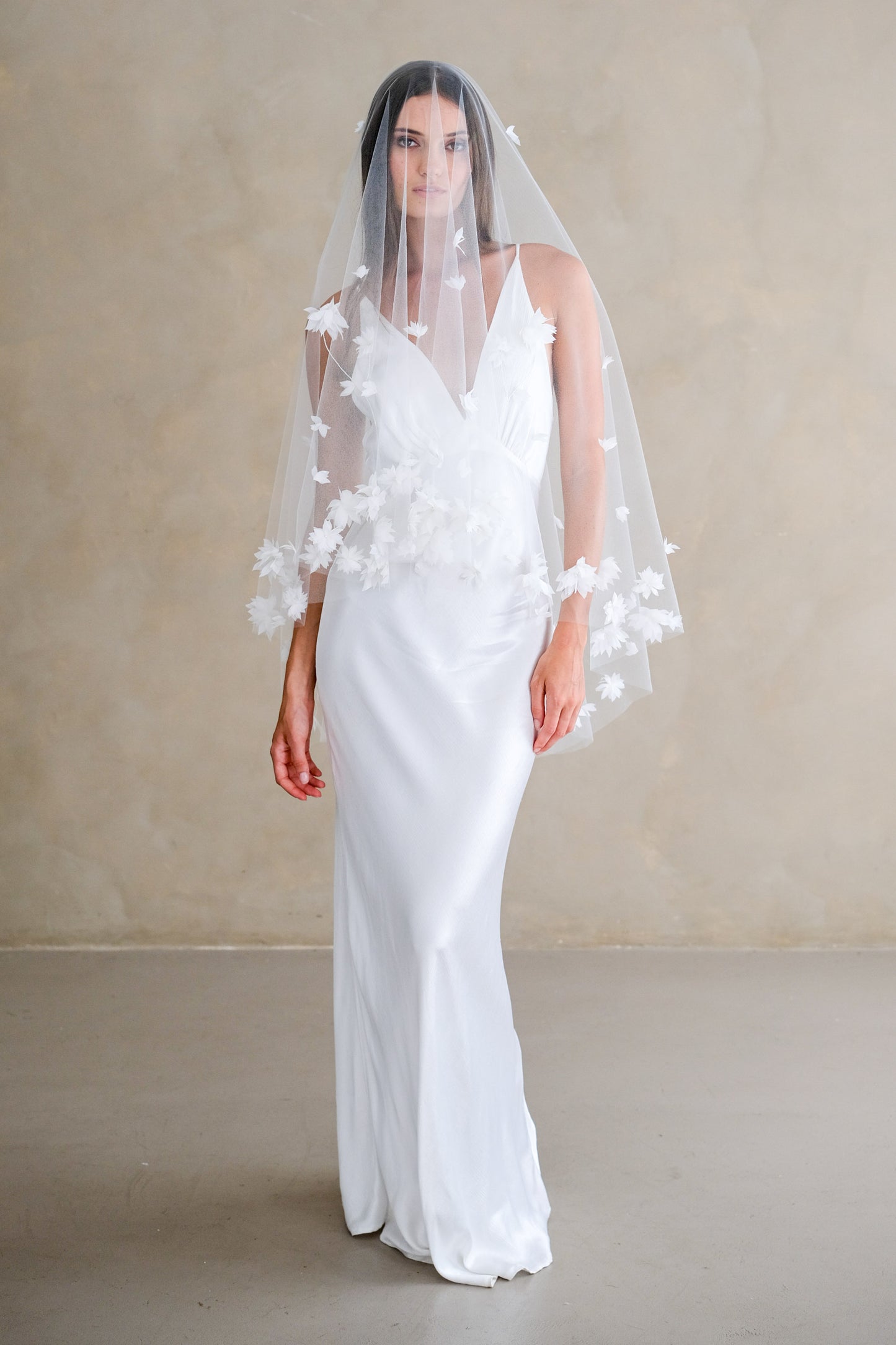 Full length front facing bride wears fingertip length veil with blusher featuring 3-D fabric flower trim and scatter