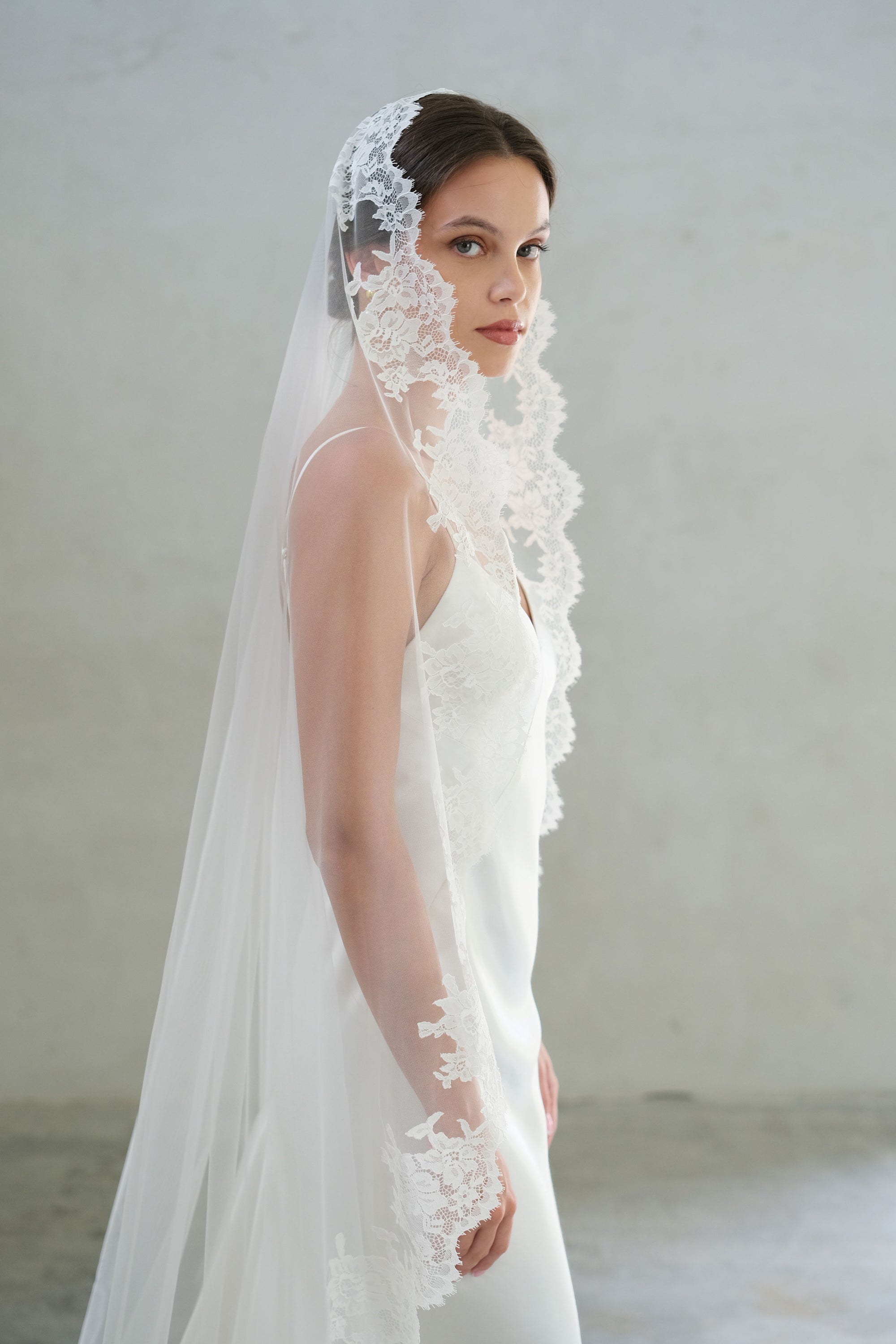 Side view of bride wearing long, lace trimmed mantilla veil