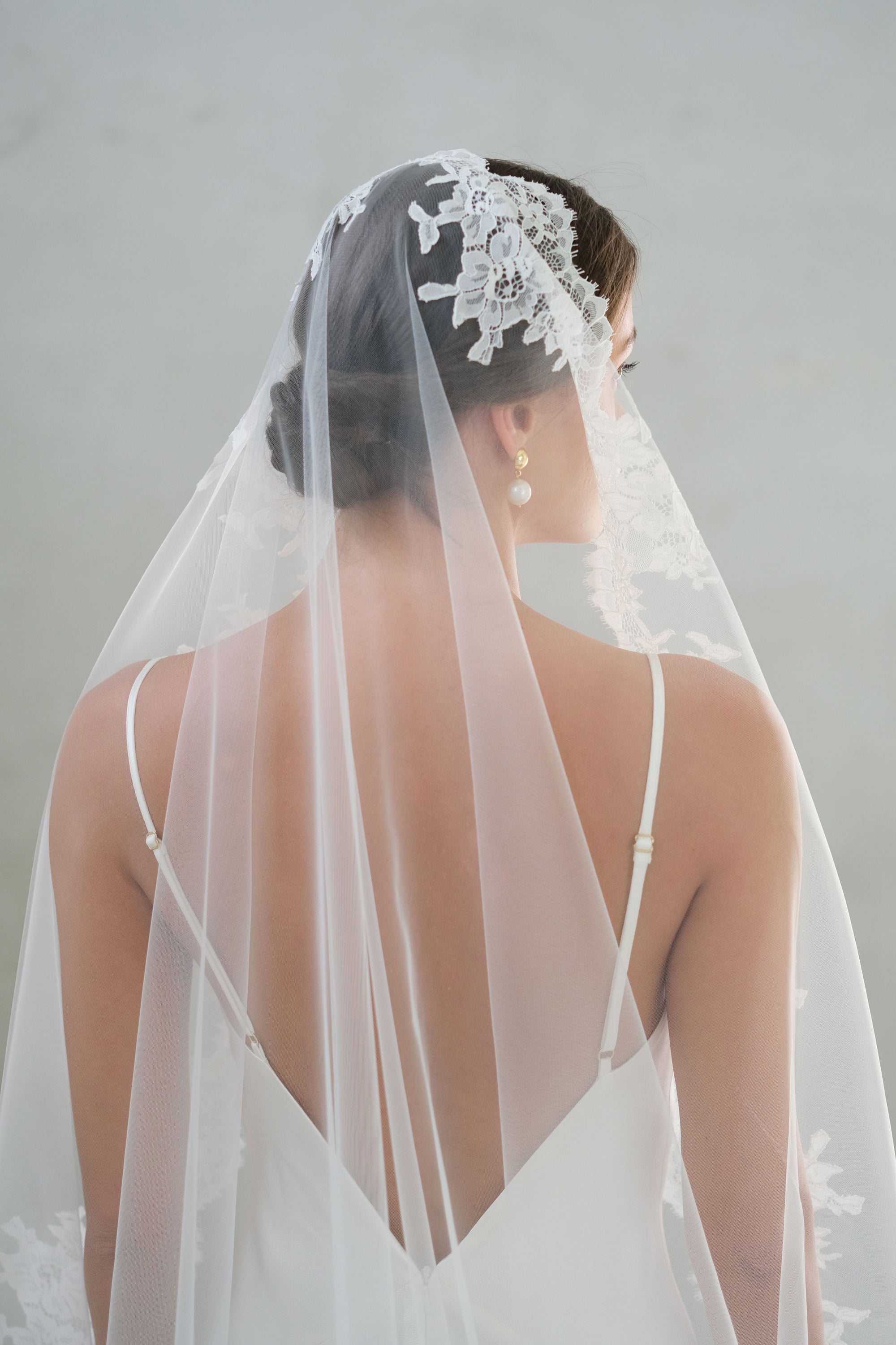 Back view, head and shoulders shot of bride wearing mantilla veil with lace trimming