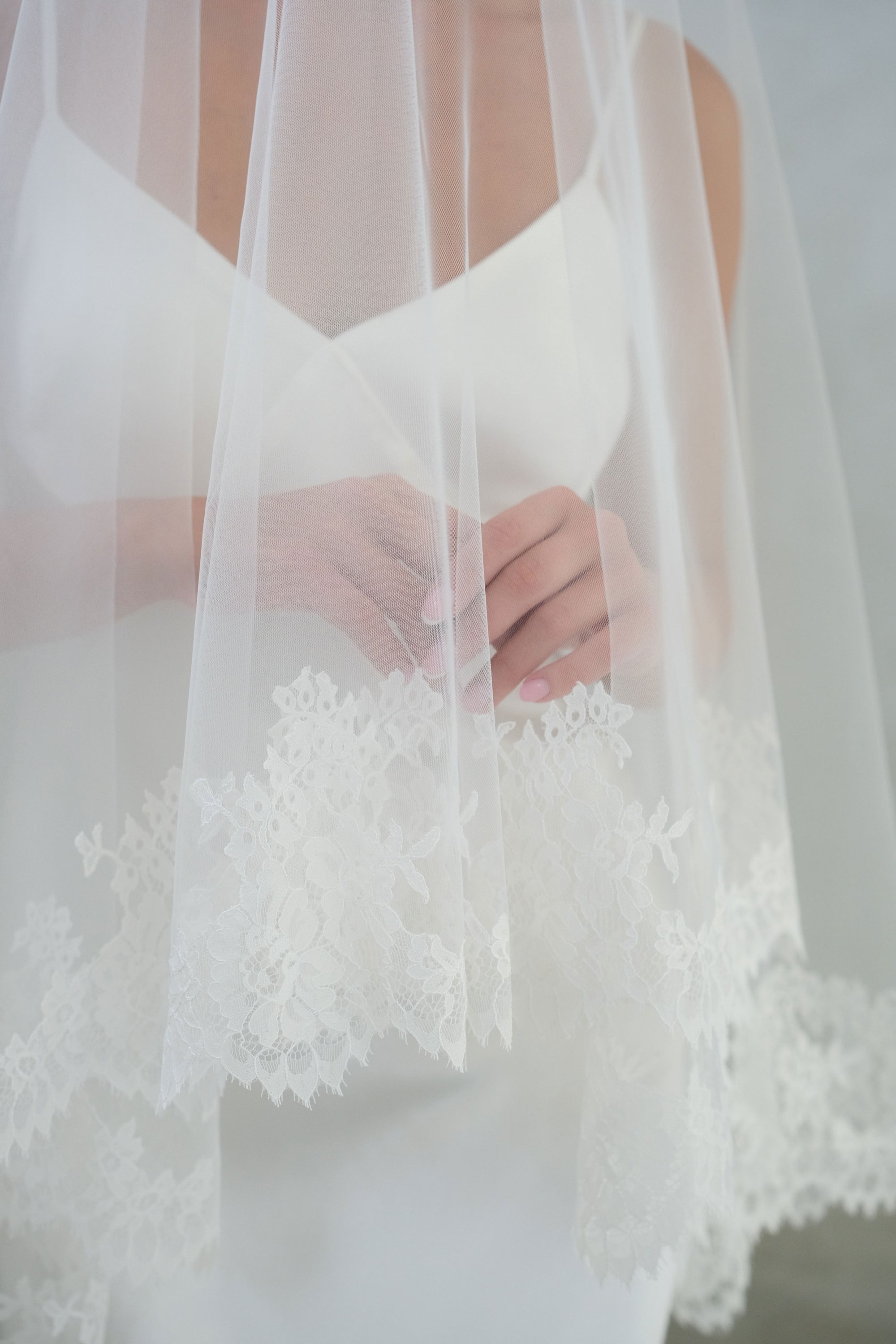 Close up detailing elaborate lace edging on two tier wedding veil blusher