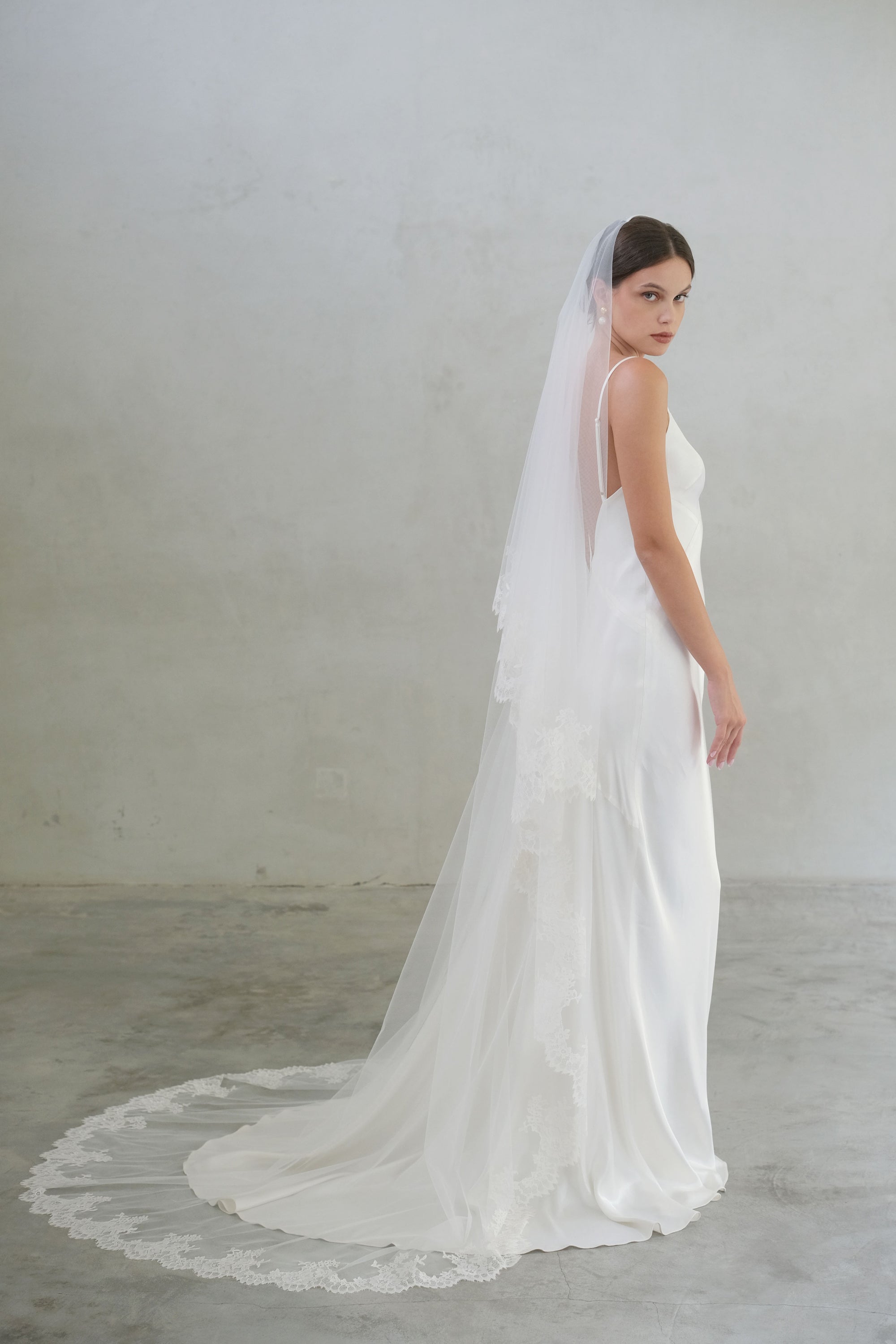 Bride turns to show full length of two tier lace trimmed veil with blusher off