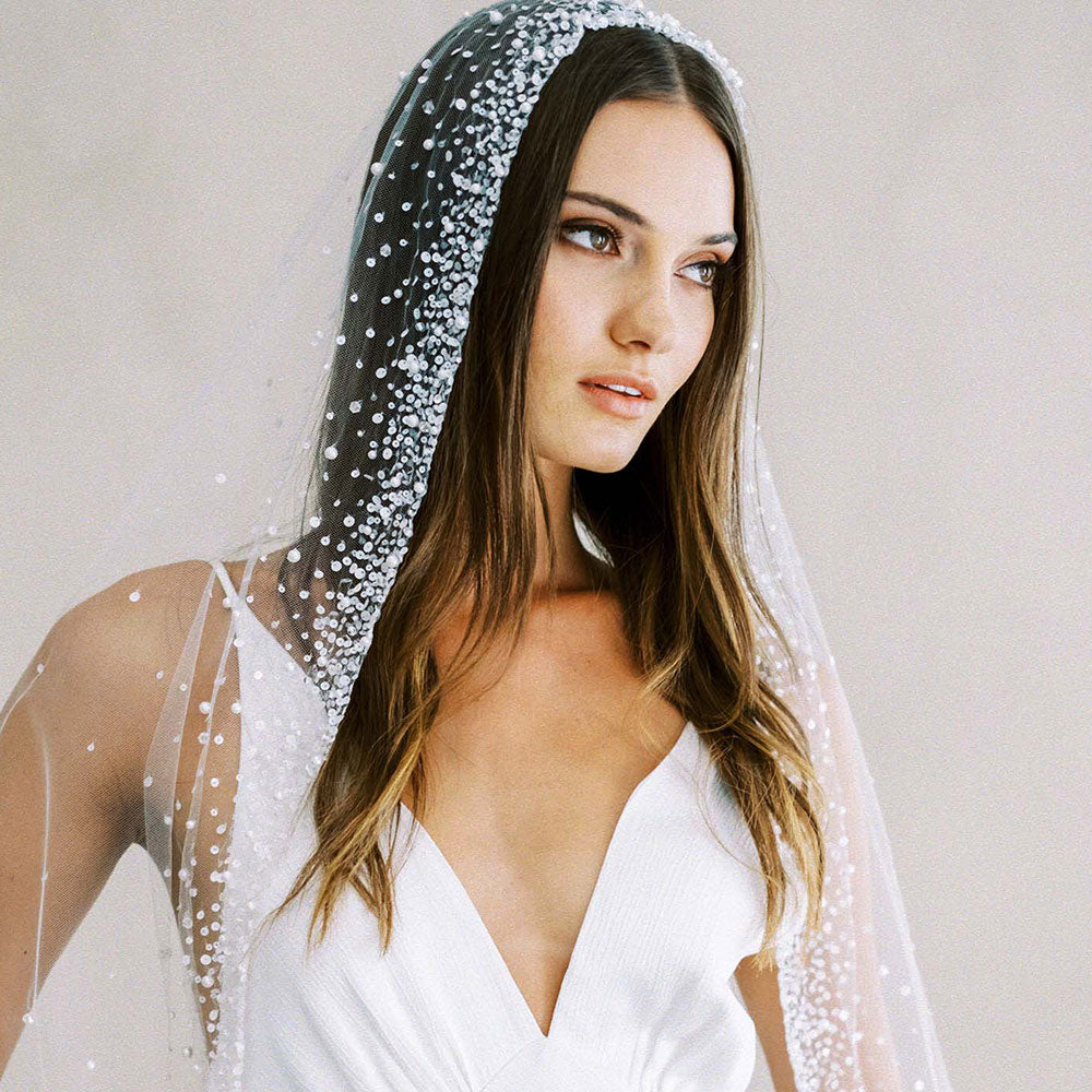 Head and shoulders shot of bride modelling mantilla style wedding veil edged with a graduating scatter of tiny crystals, pearls and sequins