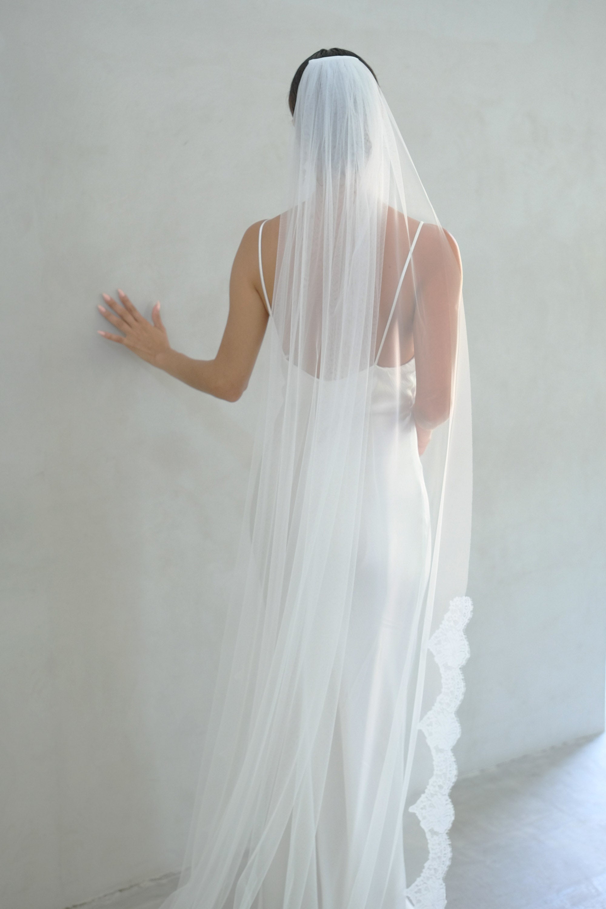 model wears one tier veil with partial lace trim, lace edged wedding veil
