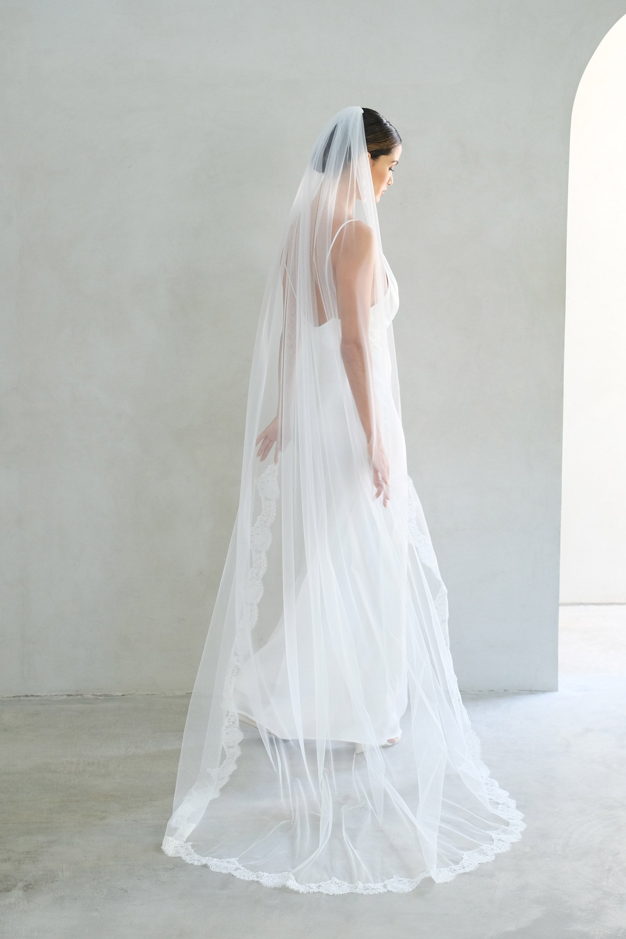 model wears one tier veil with partial lace trim, lace edged wedding veil