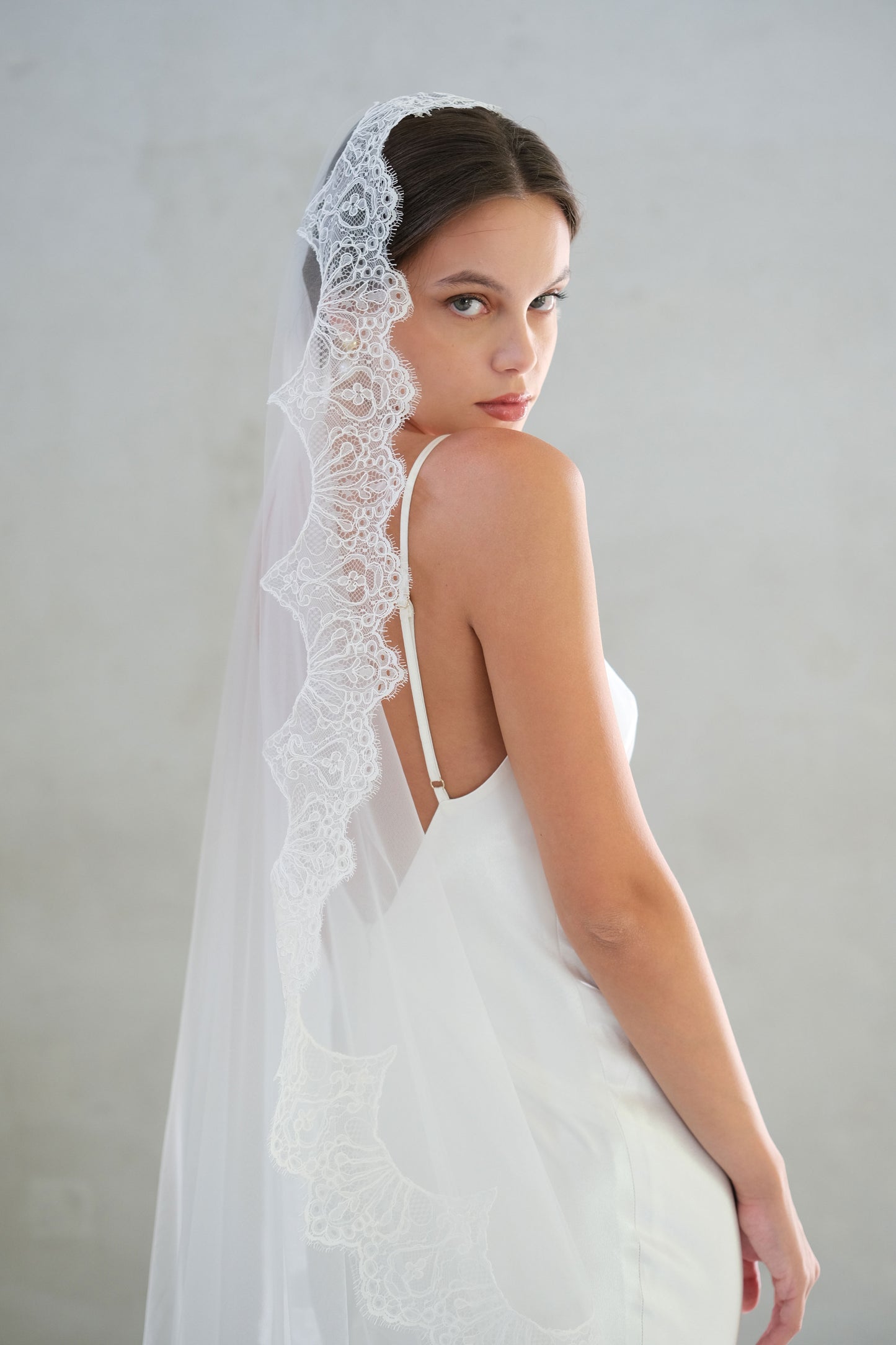 Half length shot showing delicate lace trim on mantilla style bridal veil