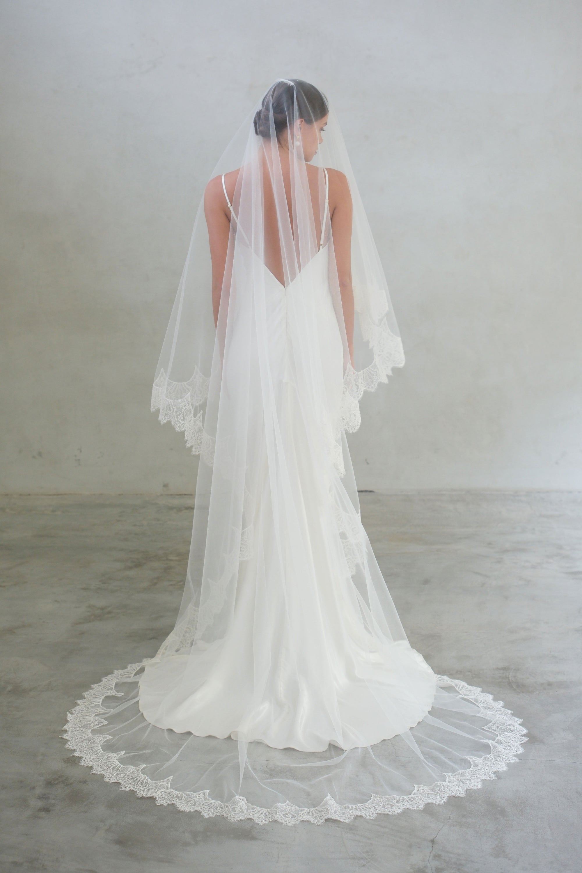 Full length back view of long two tier lace trimmed bridal veil, shown with blusher down 