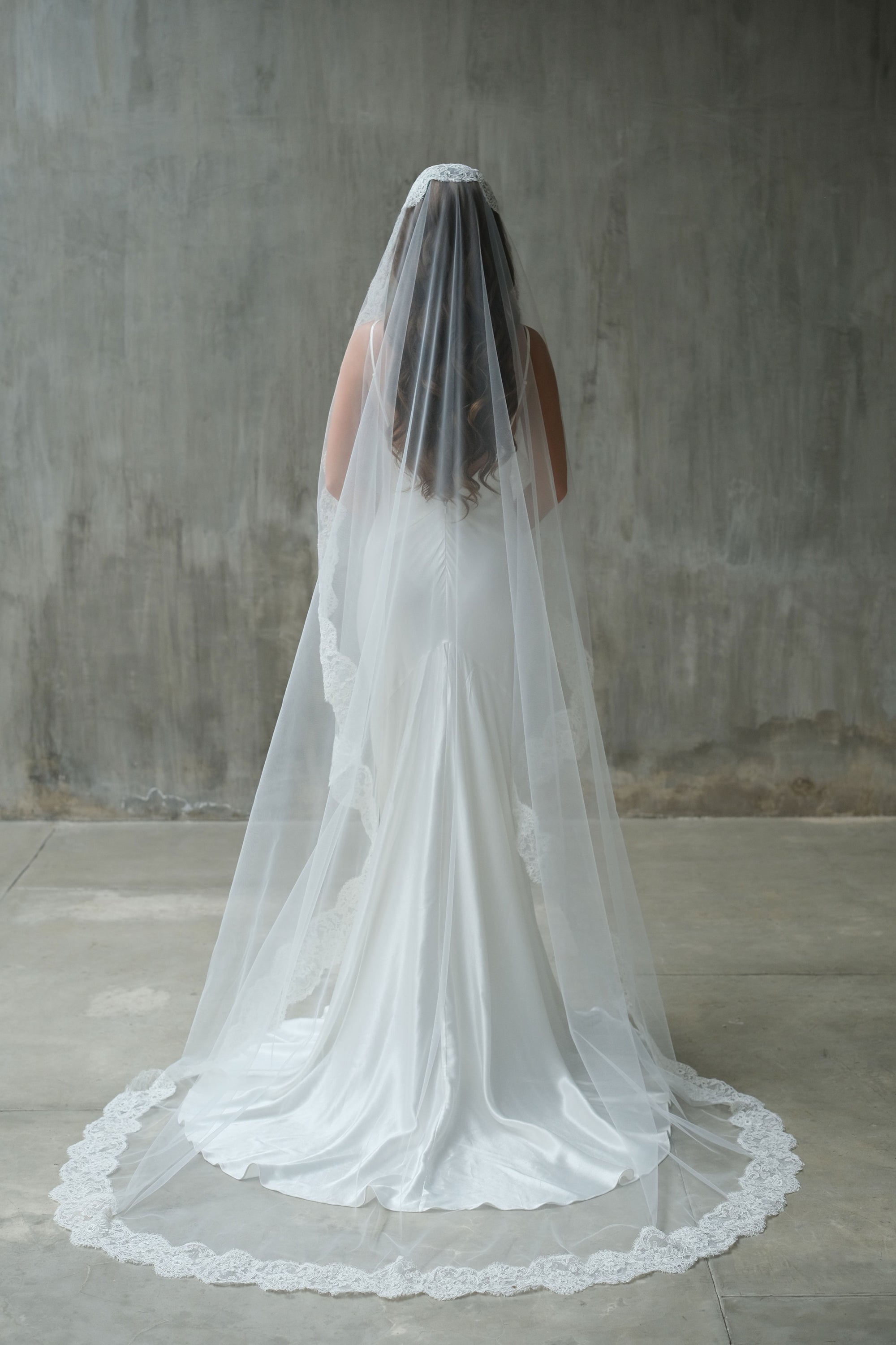 Full length back view of chapel length mantilla style bridal veil with floral lace trim