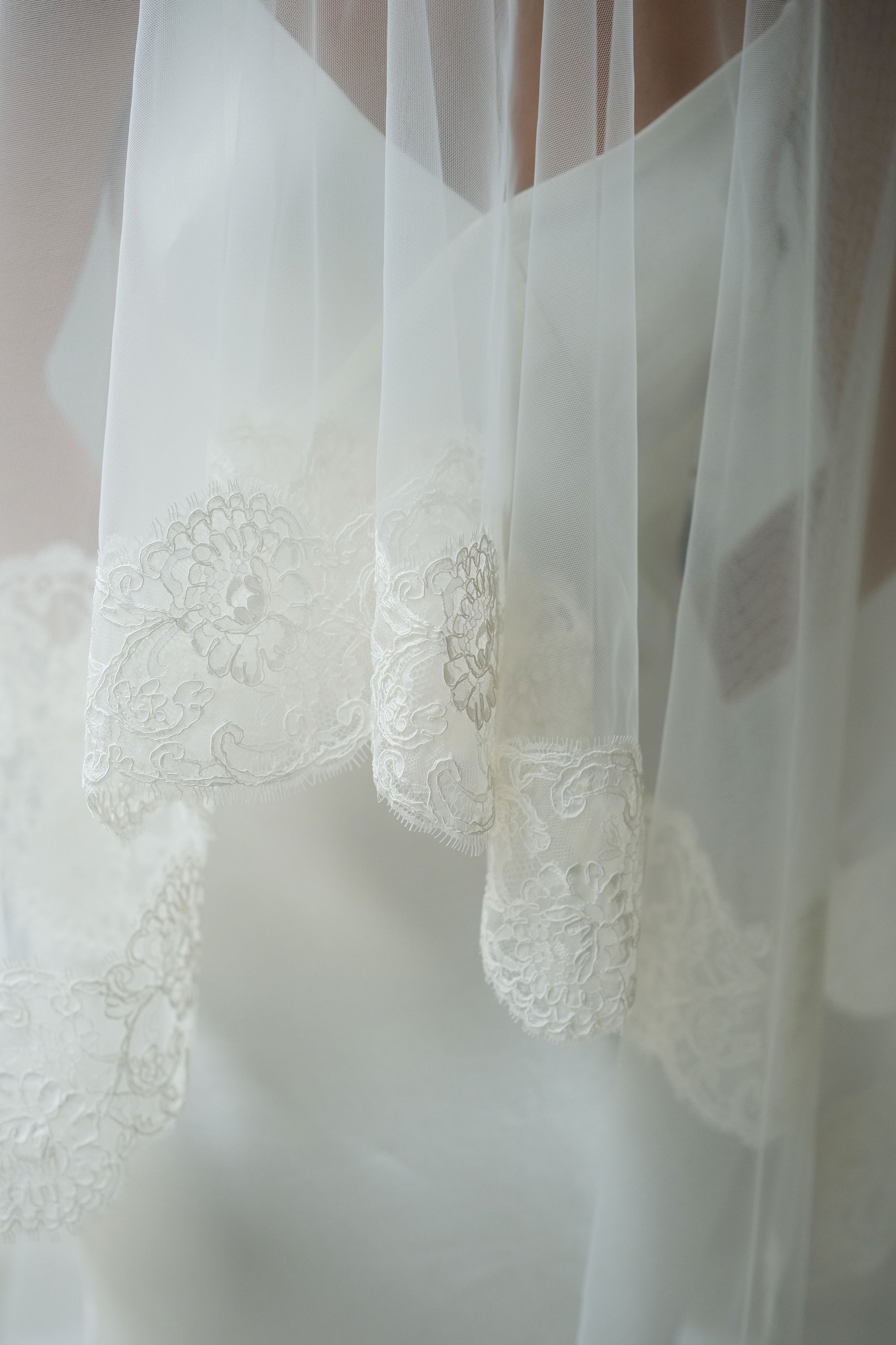 Close up shows intricate detail of lace trim on blusher of wedding veil