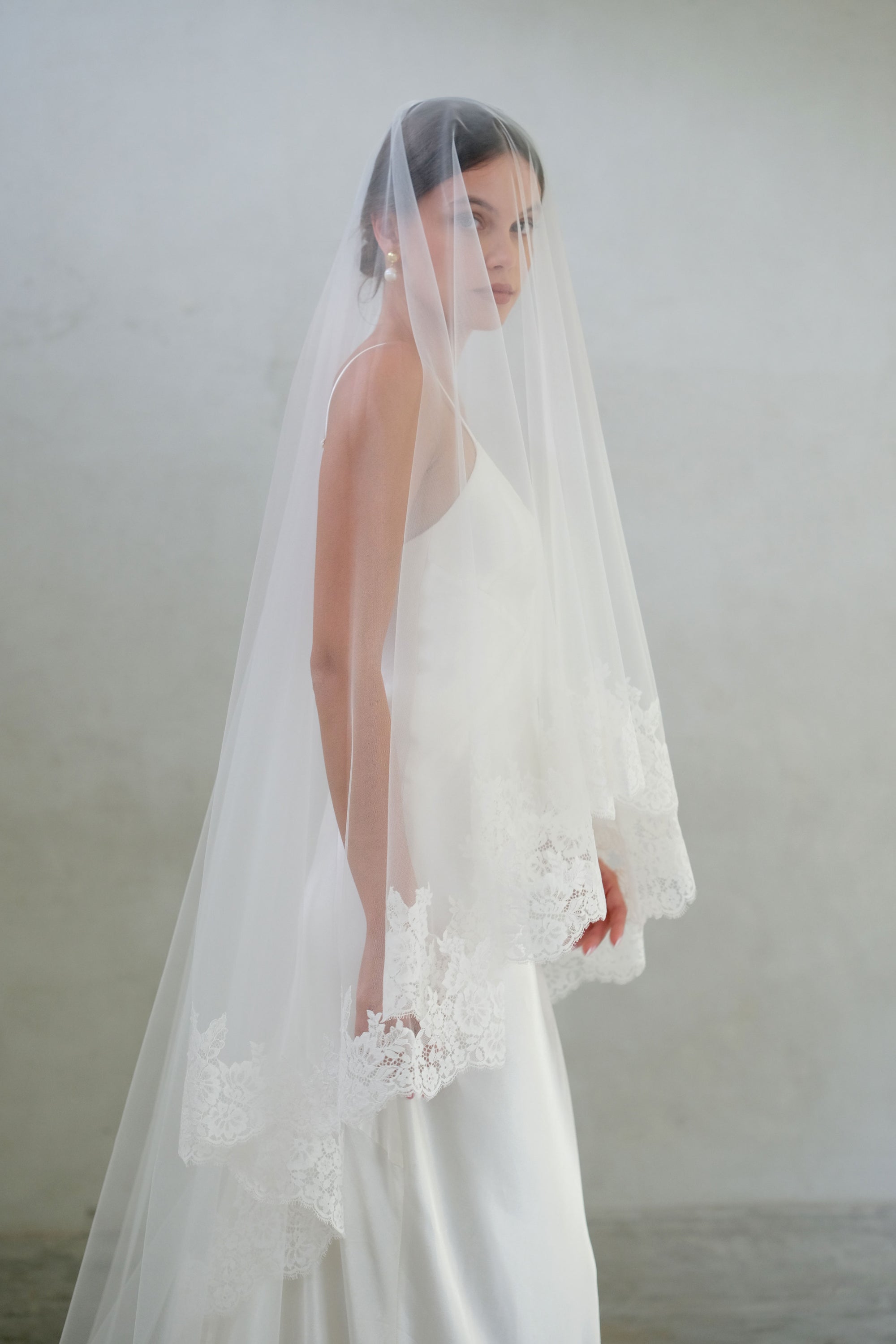 Drop veil with lace trimming is worn with blusher down in half length side view