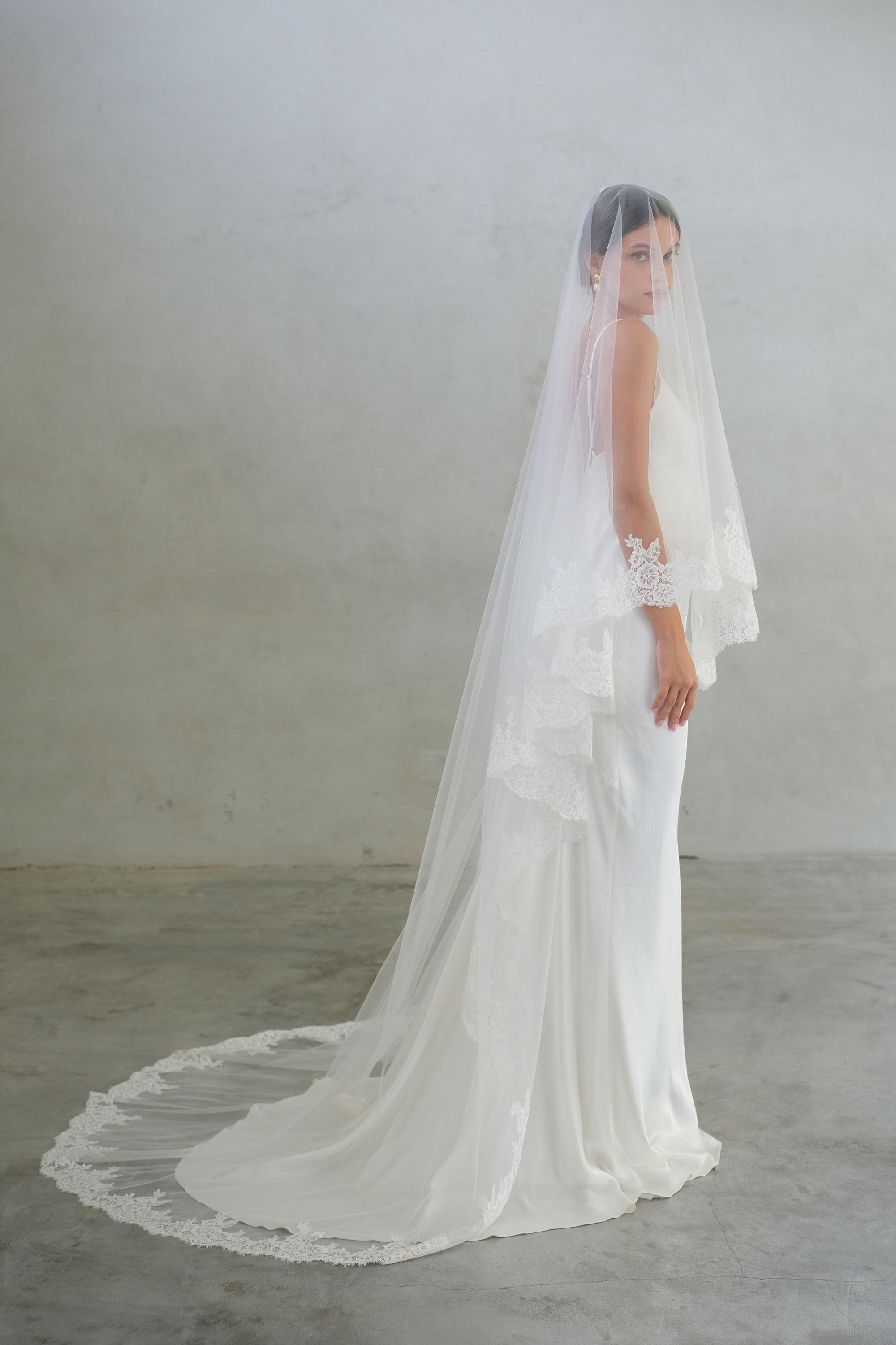 Full length side view of long romantic laced trimmed veil, blusher down