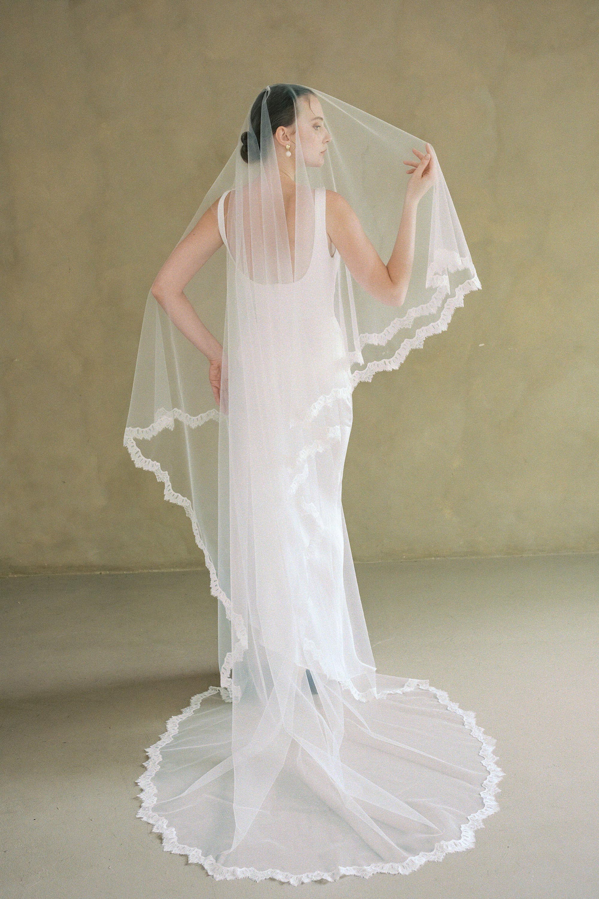 model wears drop veil, two-tier Mantilla lace trim wedding veil