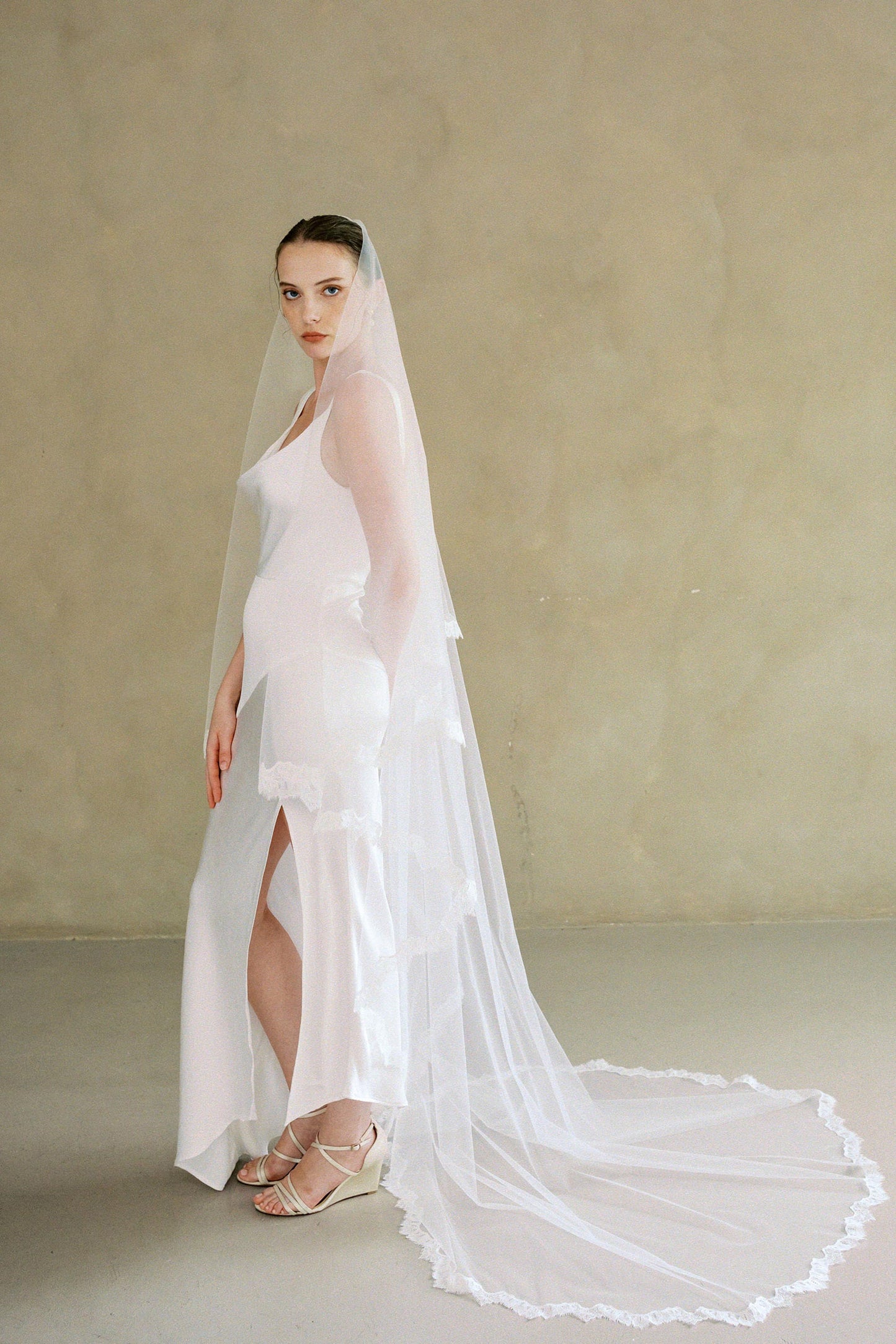 Side view of model wearing drop veil, two-tier Mantilla lace trim wedding veil with blusher off