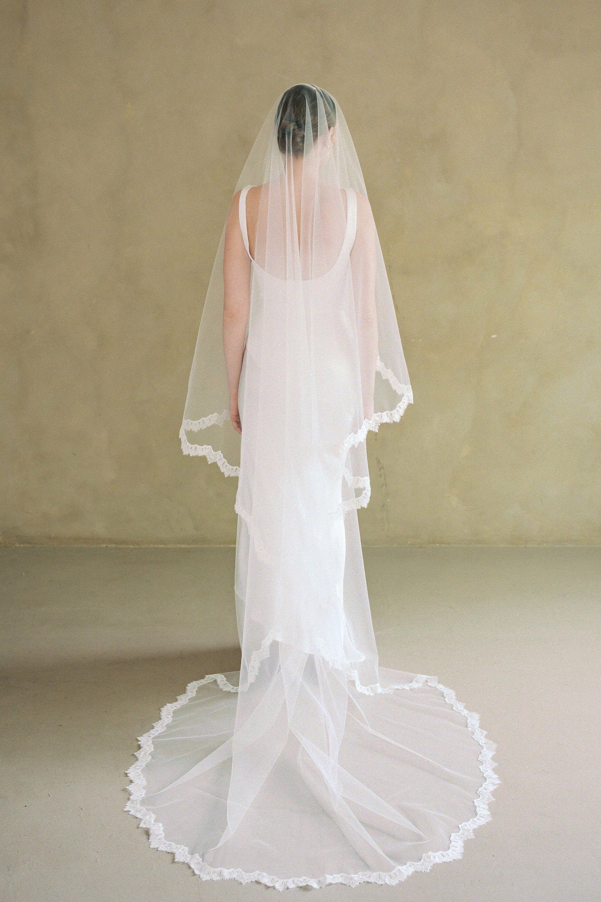 model wears drop veil, two-tier Mantilla lace trim wedding veil