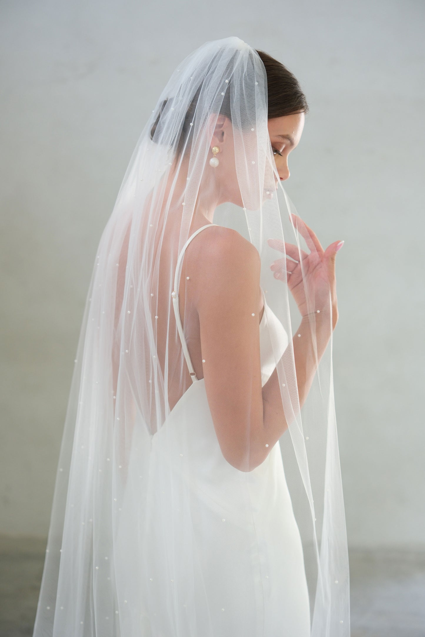 Half length side view of bridal veil gathered at the comb and embellished with tiny pearls