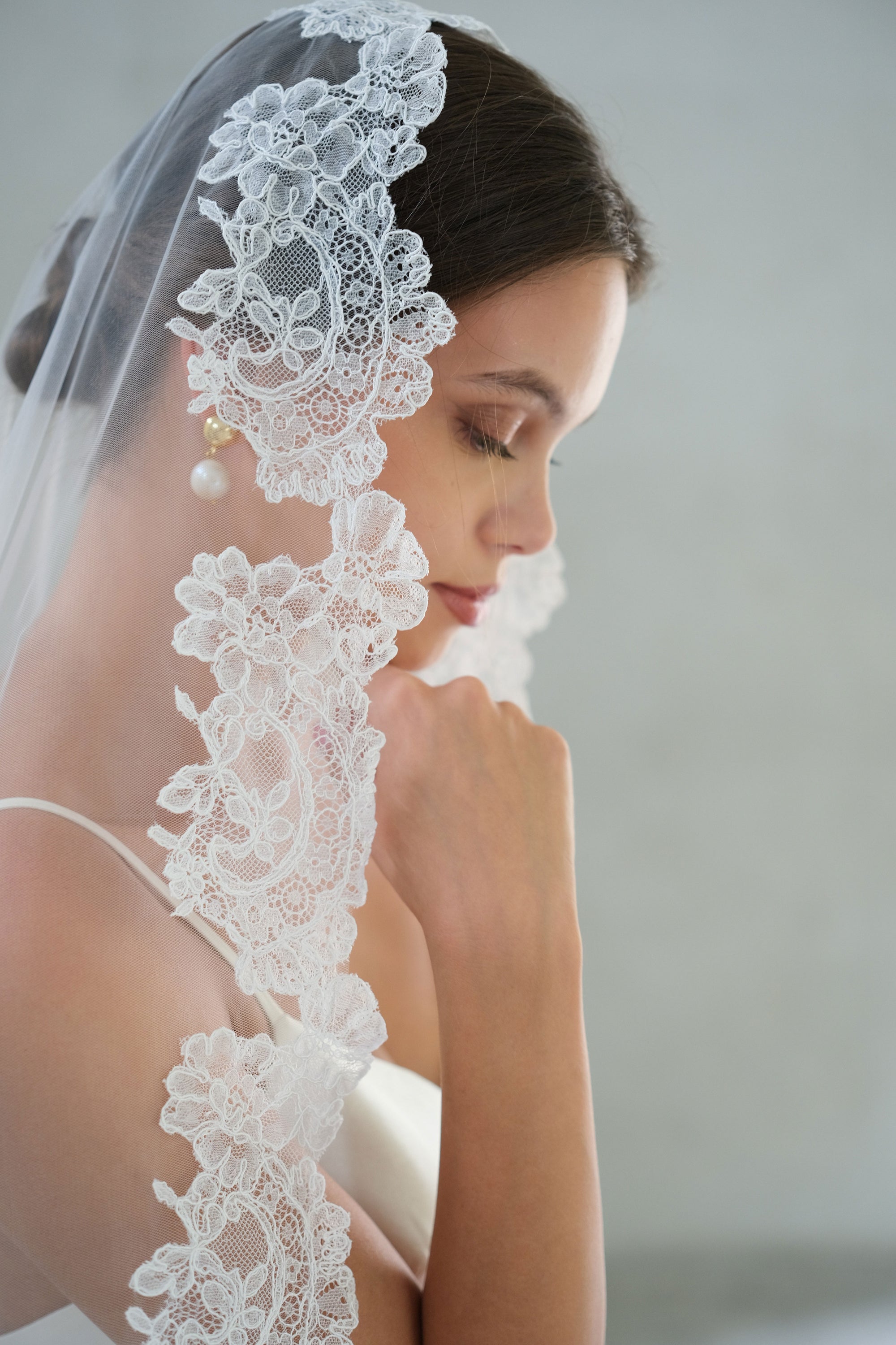 Pretty floral lace scallop edged mantilla veil drapes hair of bride in profile