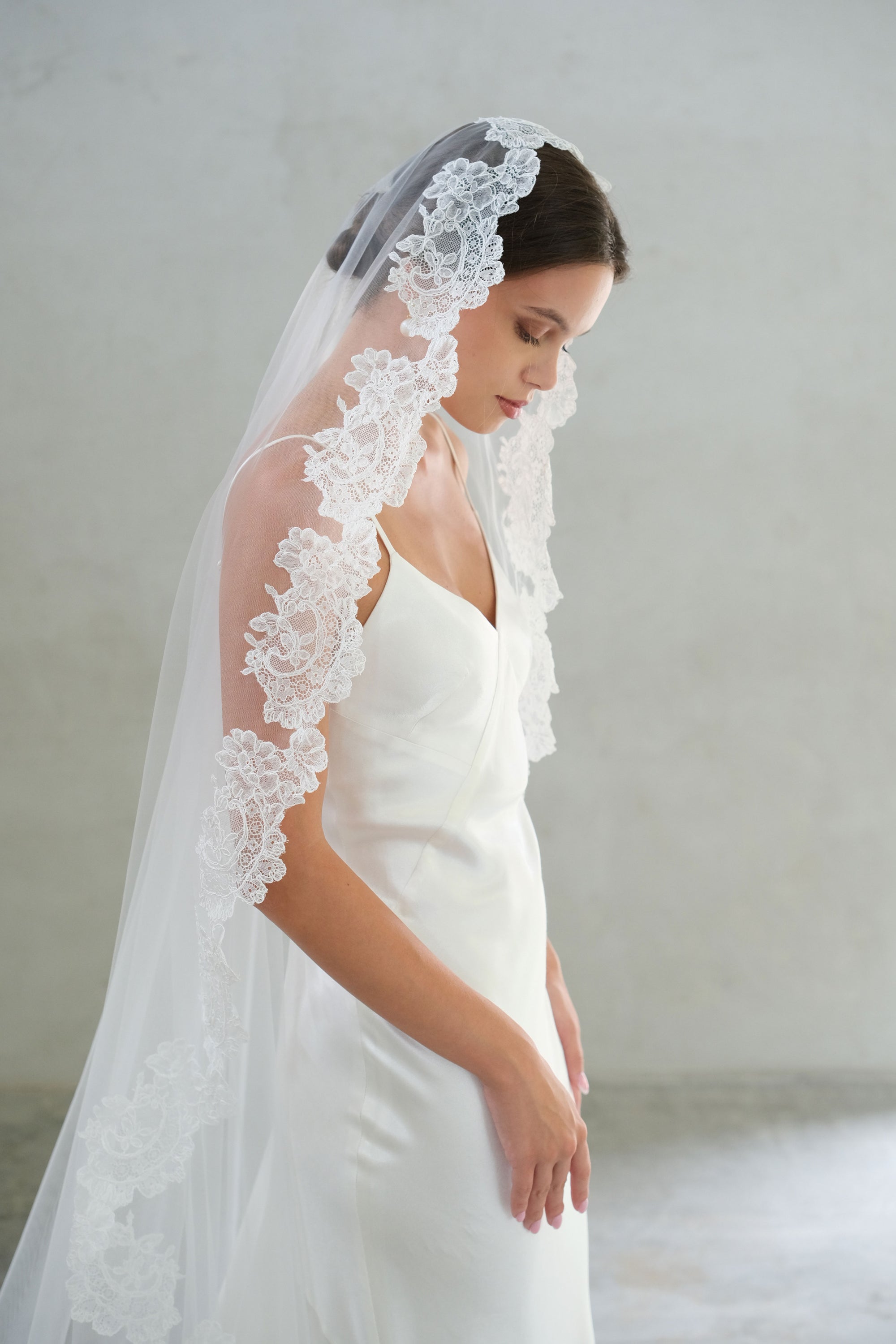 Half length side view of floral lace scallop trim on mantilla bridal veil