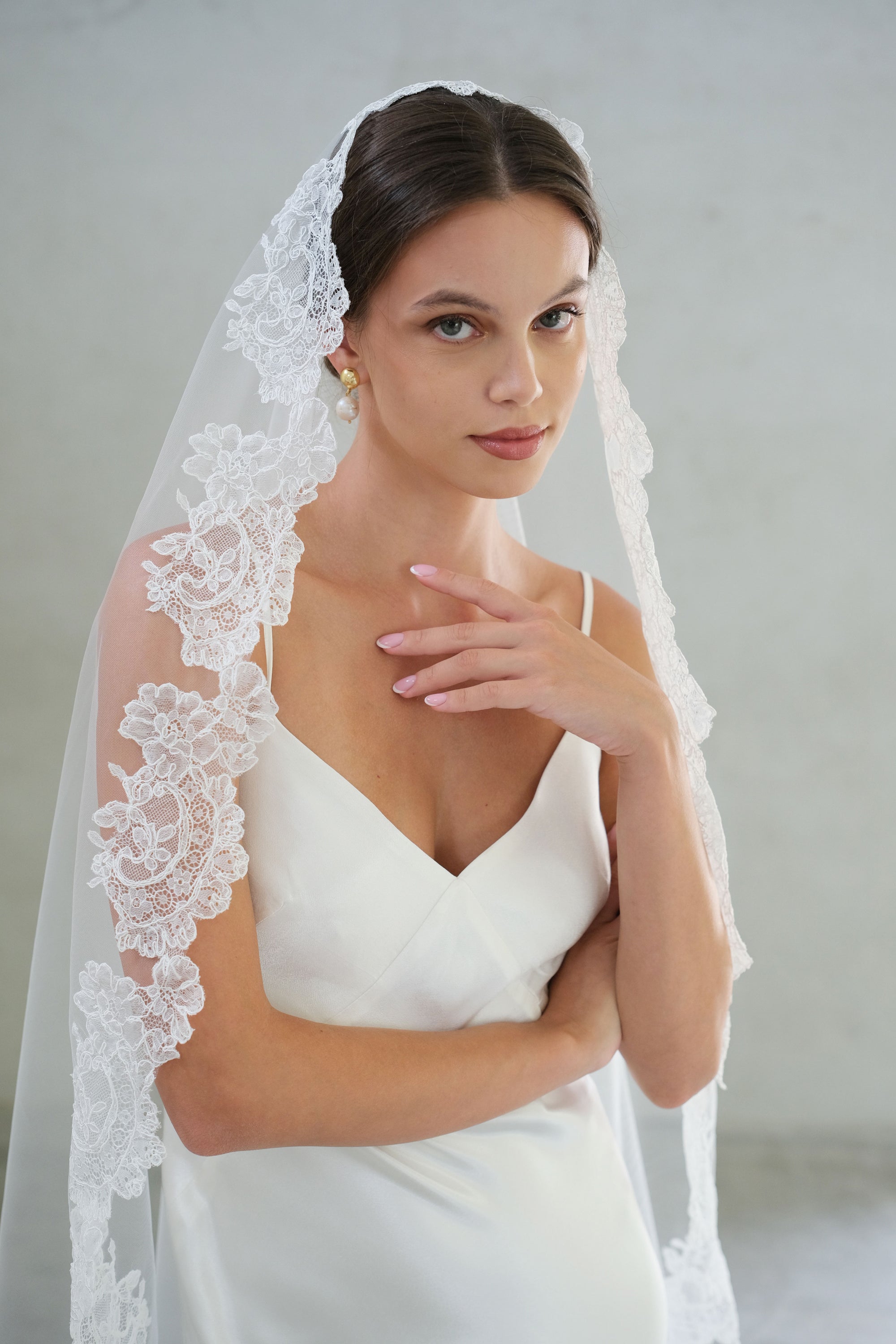Pretty floral scallops trim a mantilla veil draped over hair and shoulders