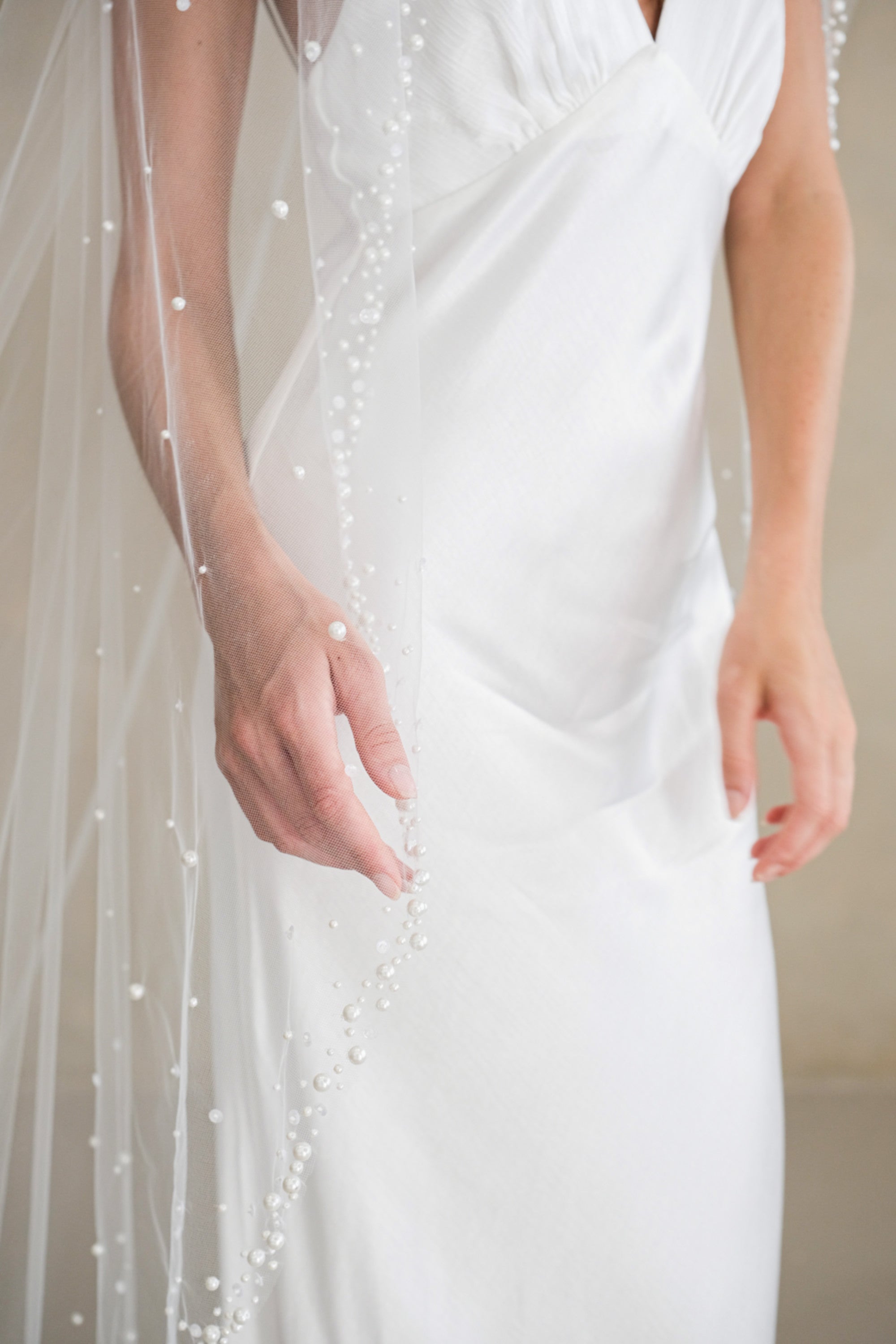 Model wears a wedding veil, one tier veil with pearls and sequins