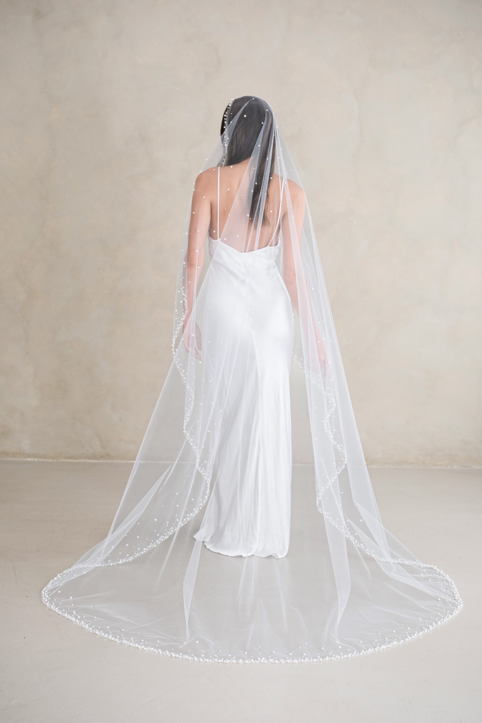 Model wears a wedding veil, one tier veil with pearls and sequins
