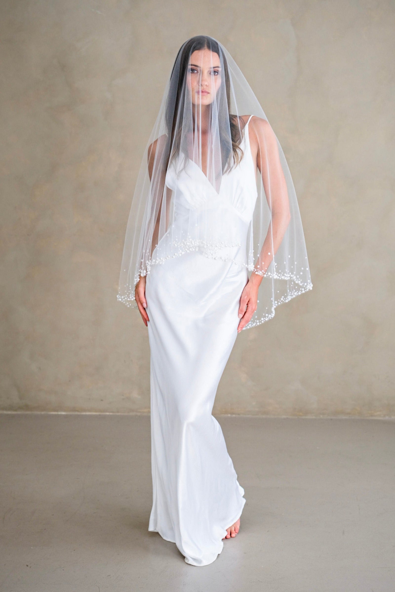 Model wears a two-tier wedding veil, drop veil with pearls and sequins