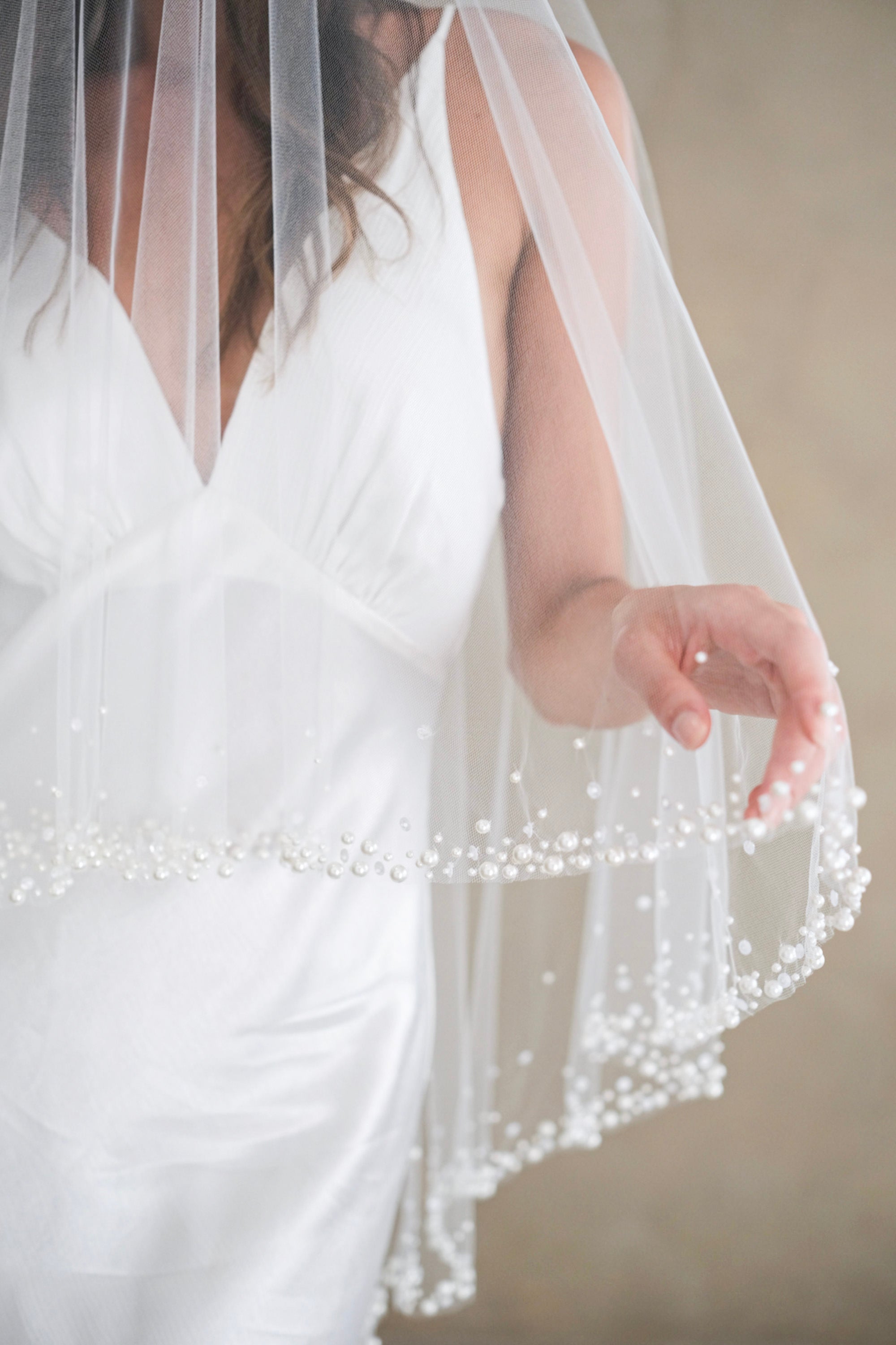 Model wears a two-tier wedding veil, drop veil with pearls and sequins