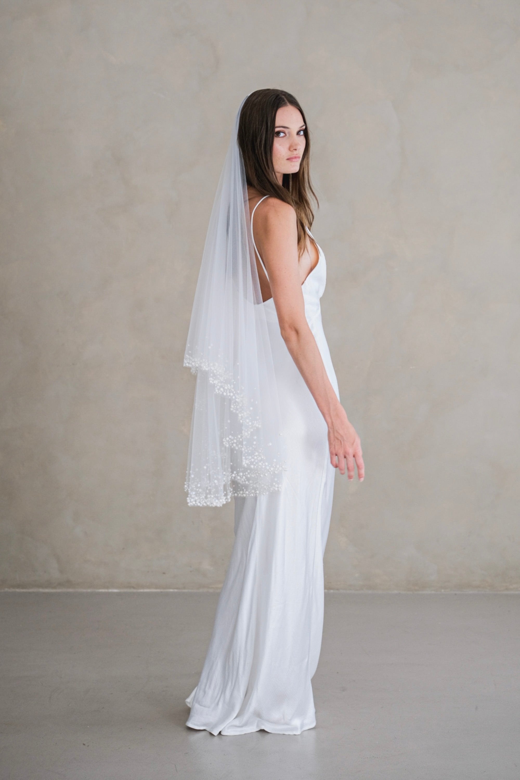 Model wears a two-tier wedding veil, drop veil with pearls and sequins