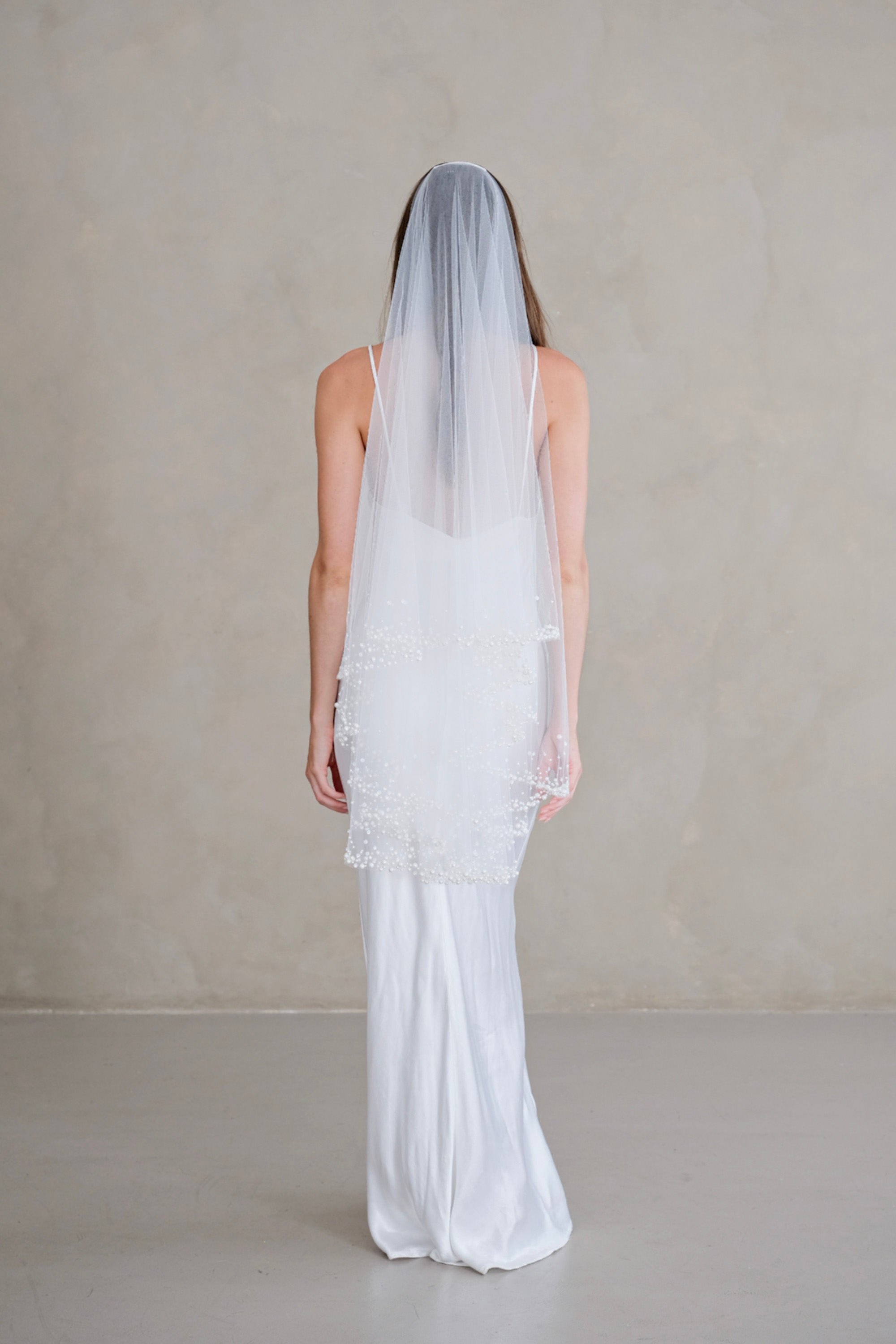 Model wears a two-tier wedding veil, drop veil with pearls and sequins