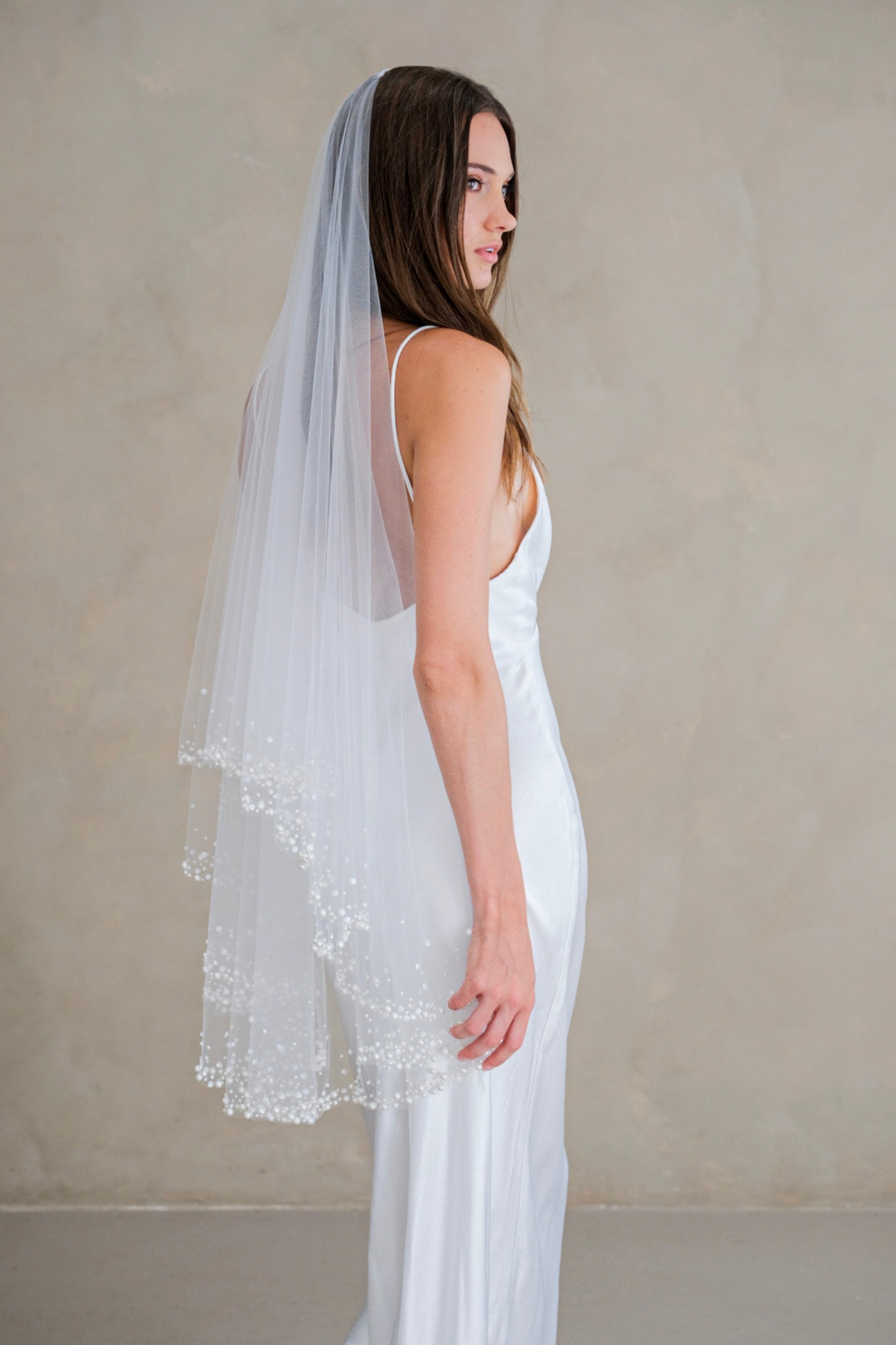 Model wears a two-tier wedding veil, drop veil with pearls and sequins