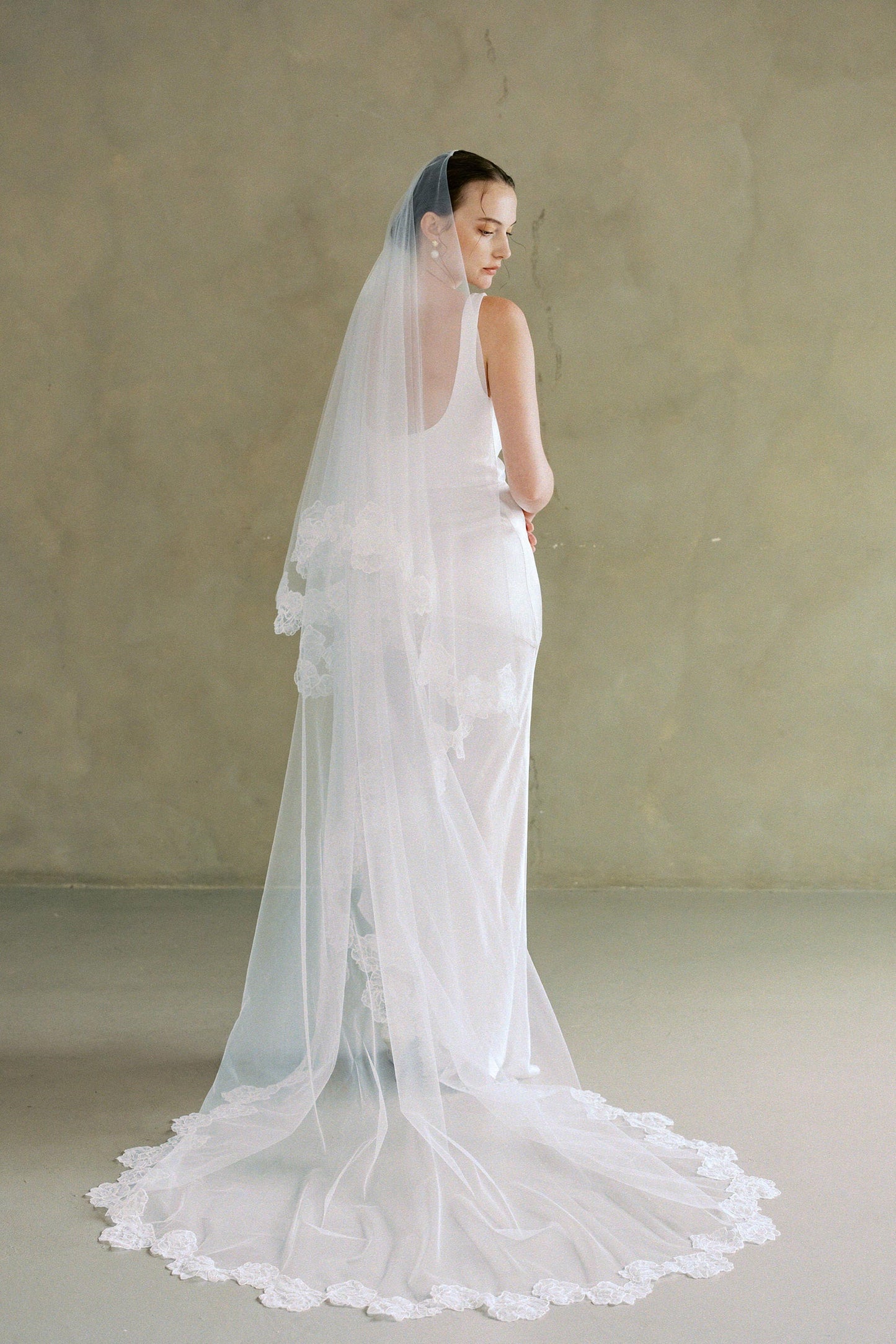 Full length back view of model wearing two-tier lace trim wedding veil; blusher off