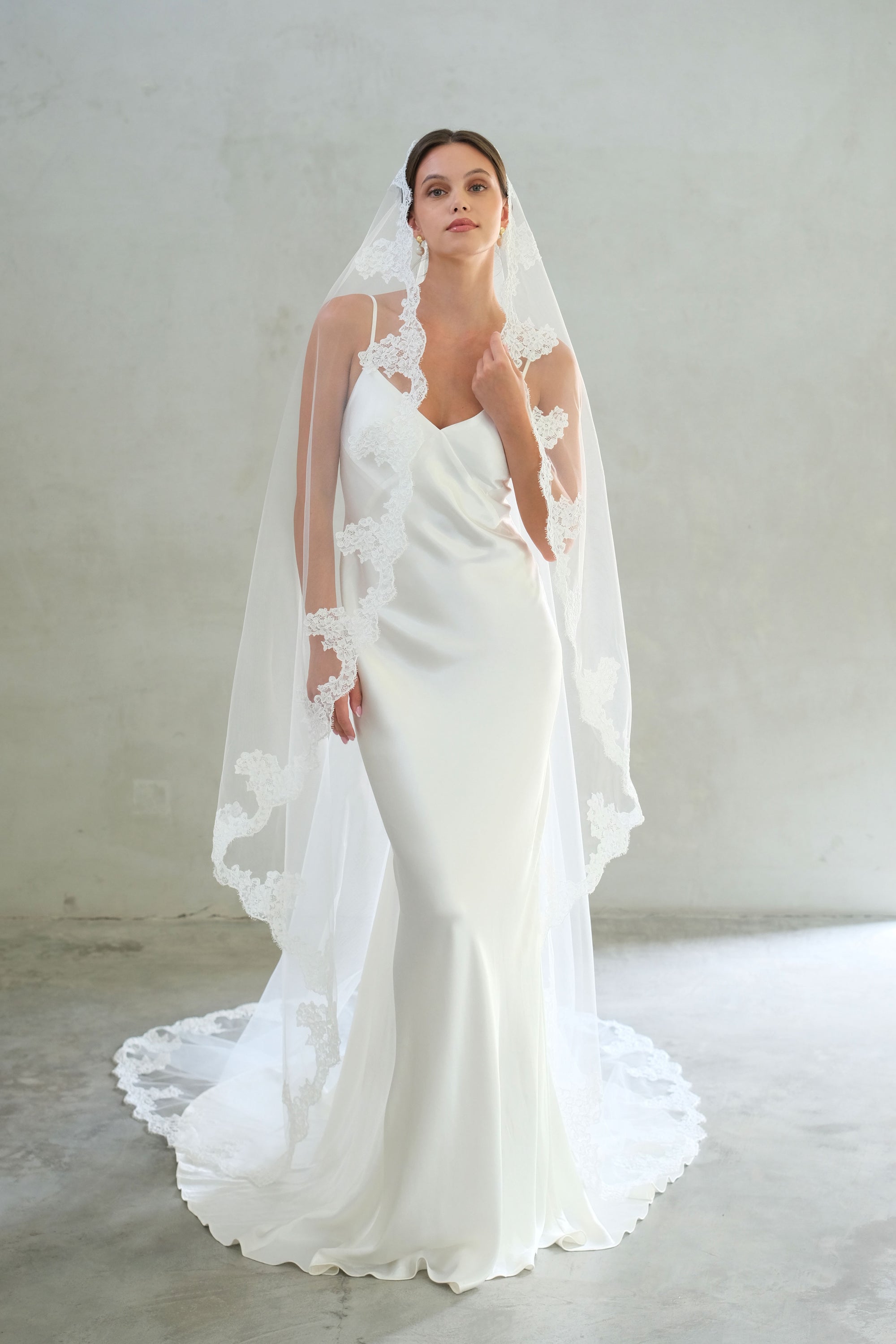 Full length fron facing bride wears chapel length mantilla veil with lace edges