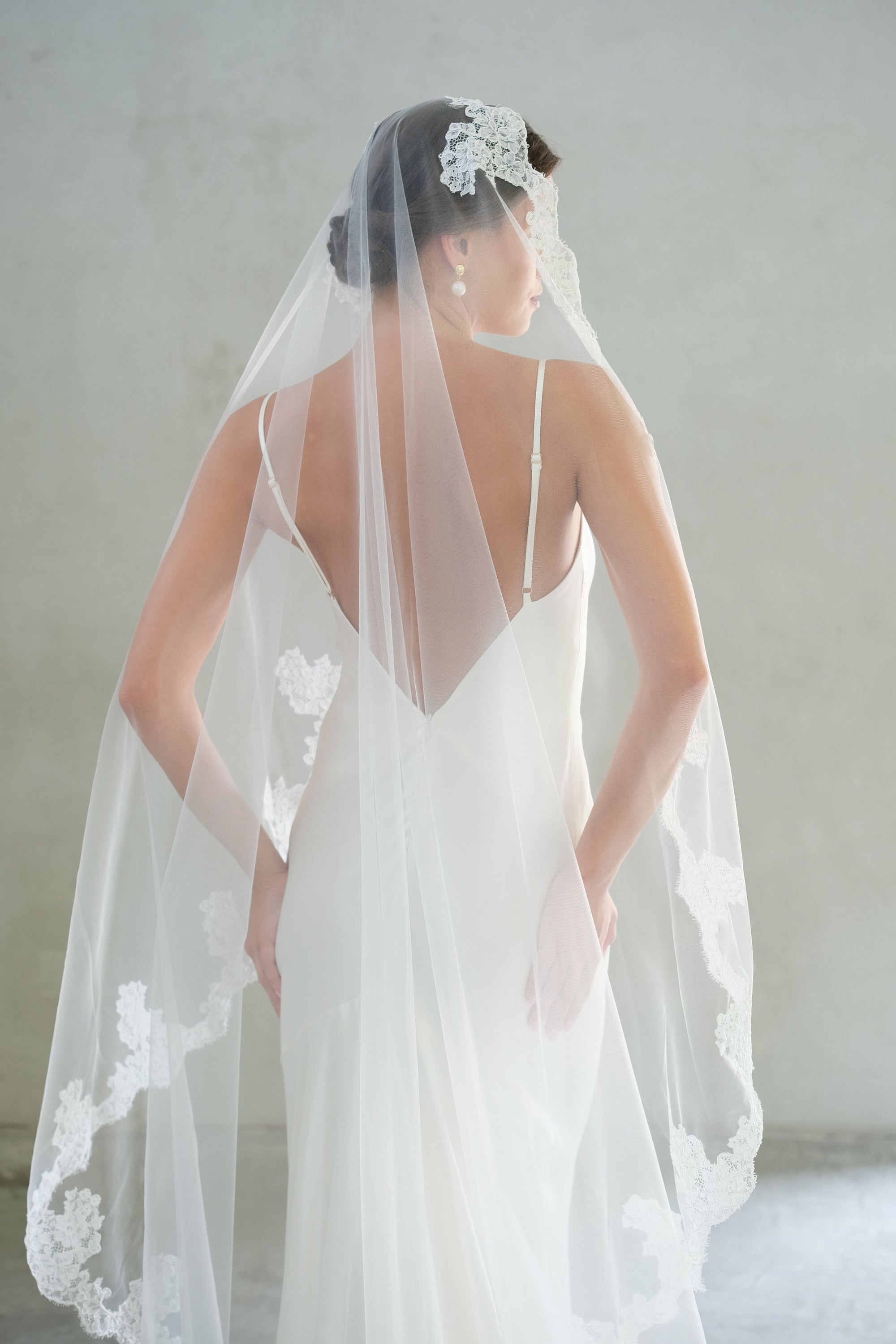 Half length back view of bride wearing mantilla veil trimmed with lace