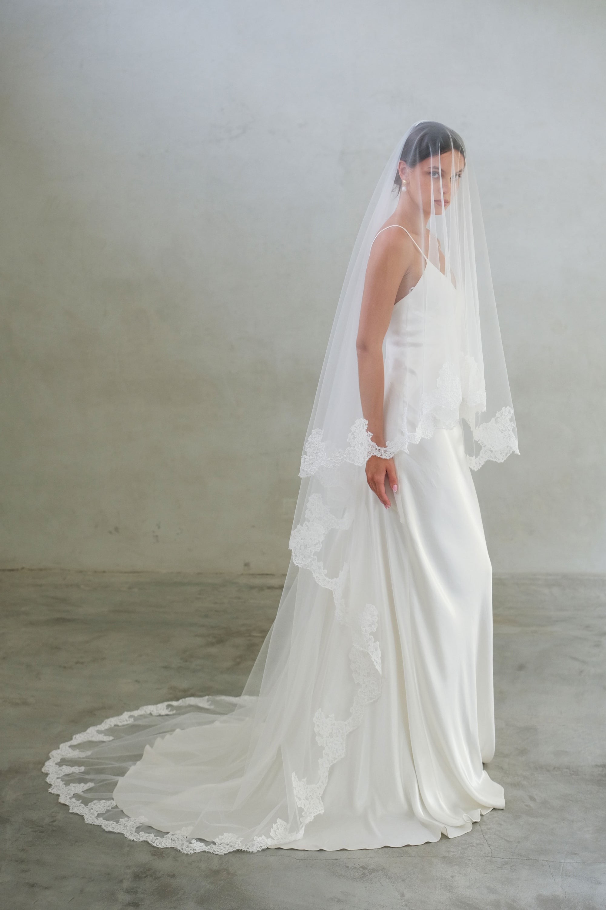 Full length side view of long, two tier wedding veil with lace trim and blusher down