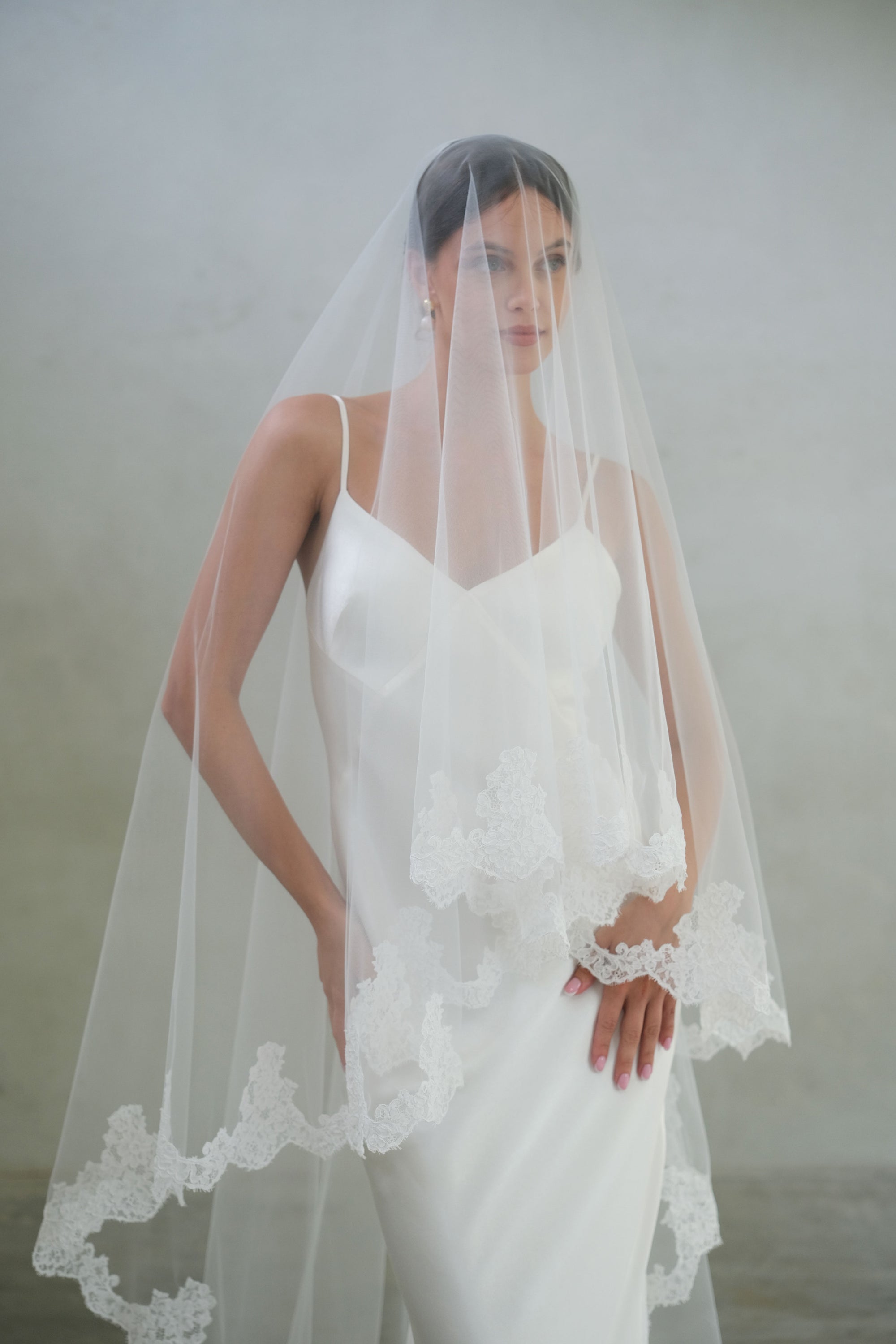 Half length shot of bride wearing two-tier wedding veil, lace trim with blusher down