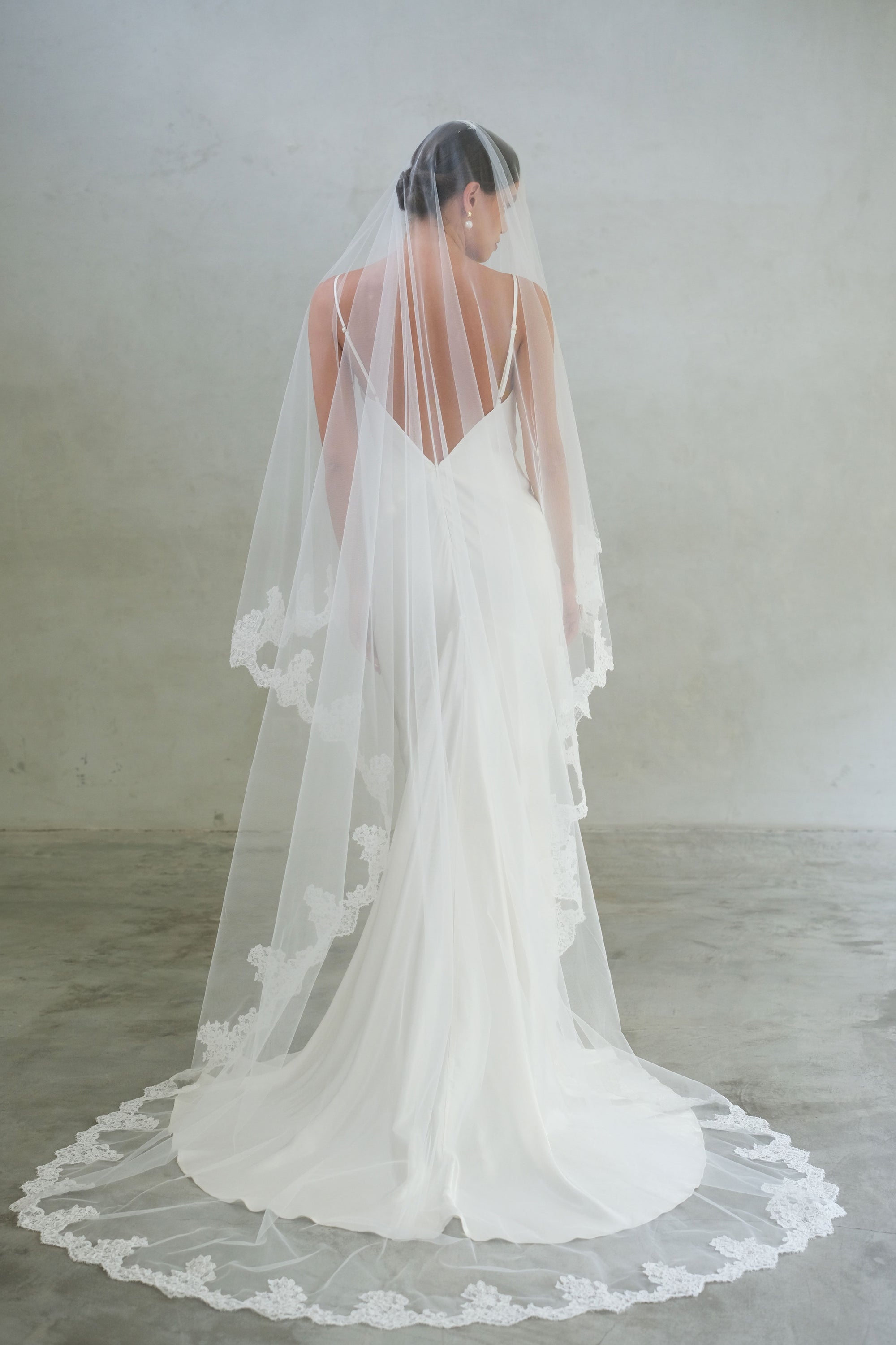 Full length back view of bride's long, lace edged wedding veil, blusher down