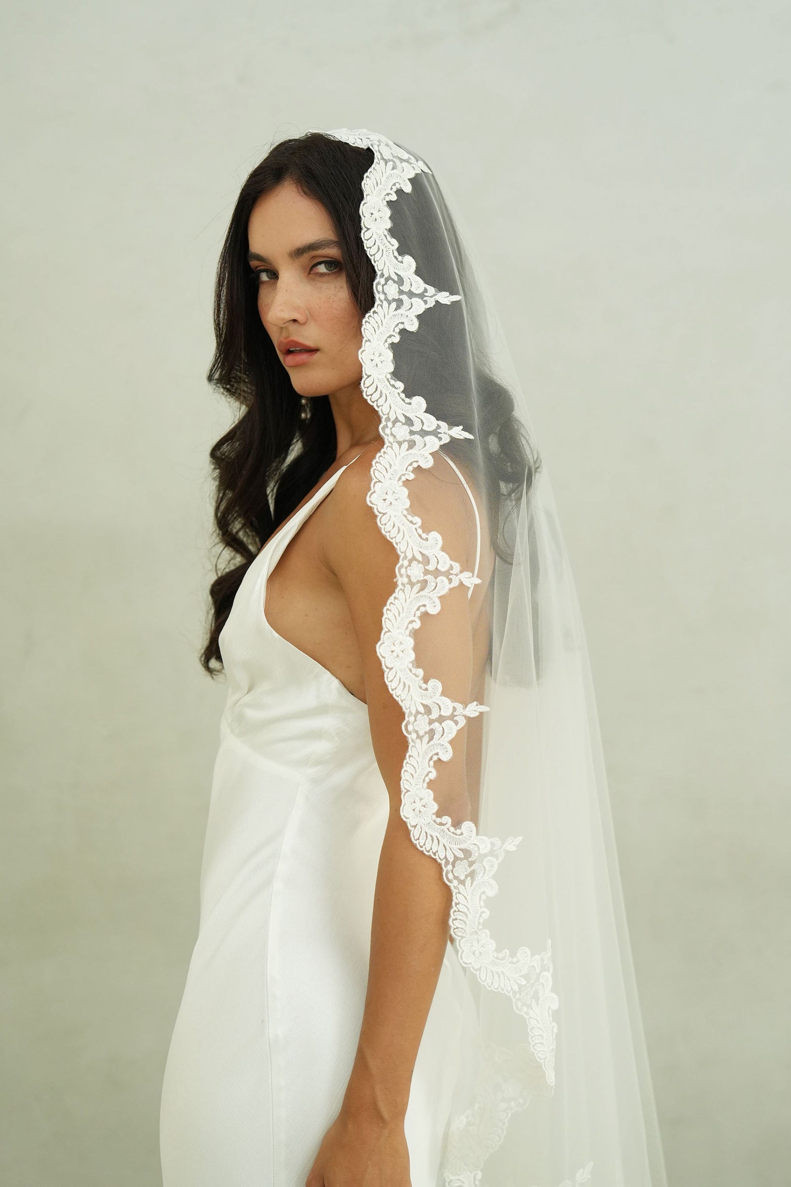 model wears mantilla veil, one-tier lace trim wedding veil