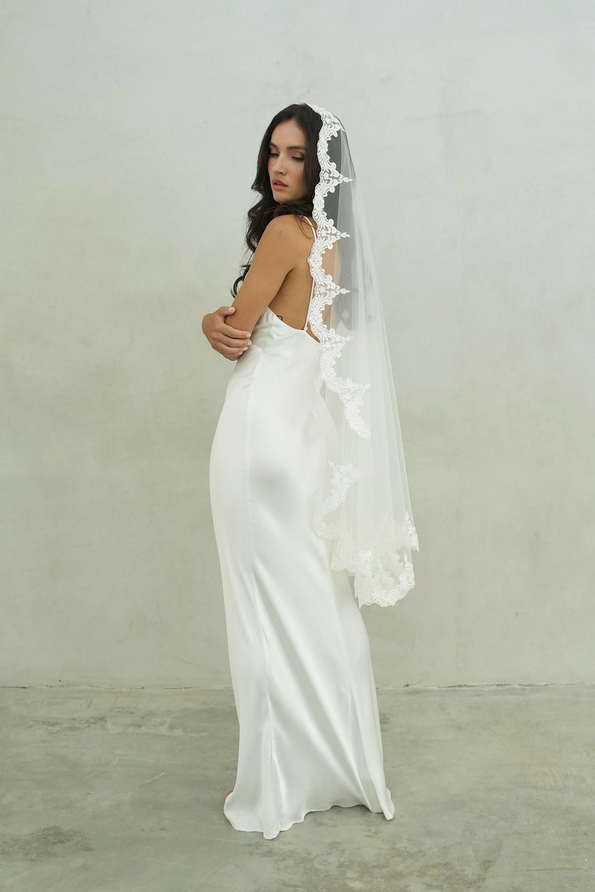 model wears mantilla veil, one-tier lace trim wedding veil