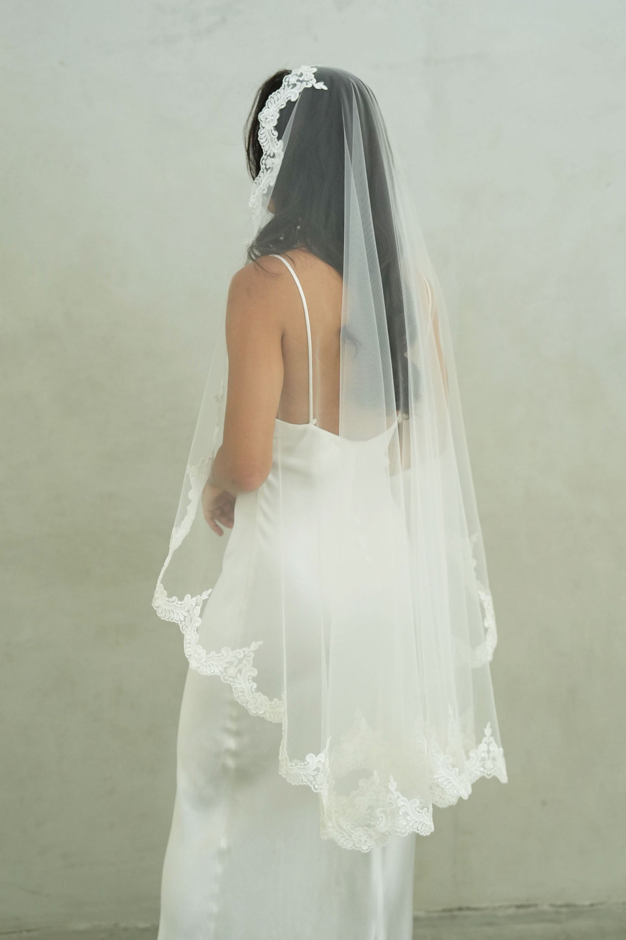 model wears mantilla veil, one-tier lace trim wedding veil