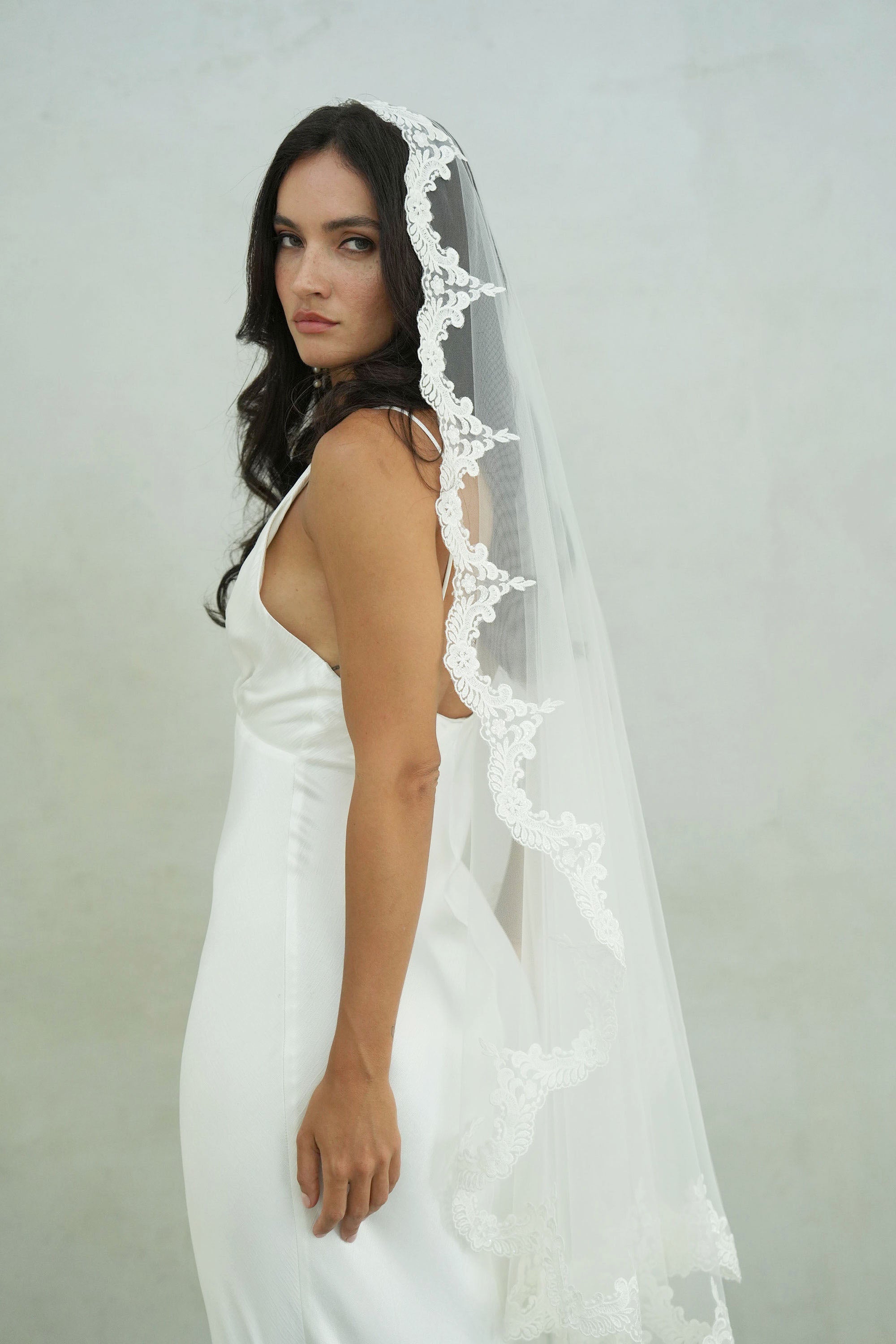 model wears mantilla veil, one-tier lace trim wedding veil