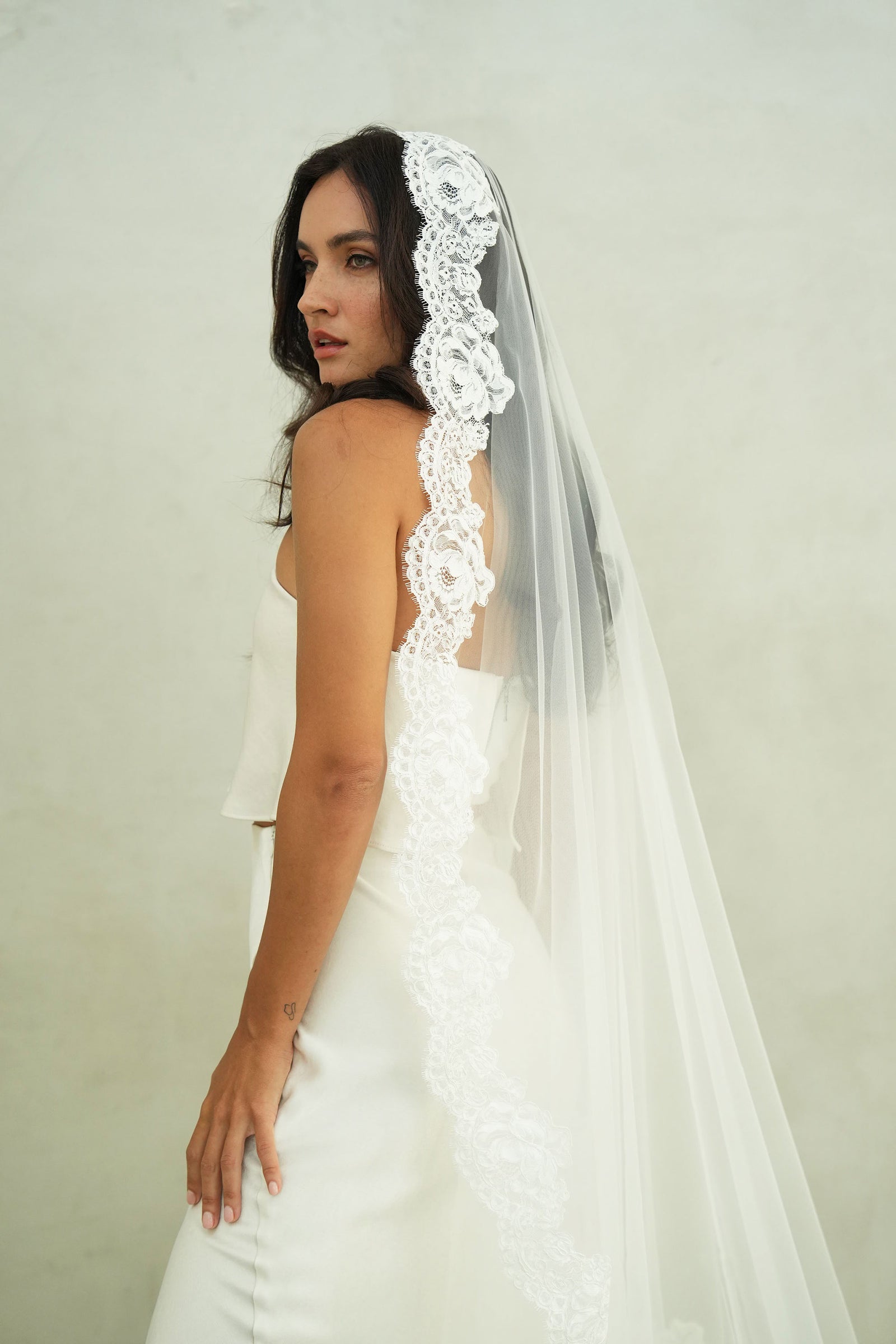 model wears mantilla veil, one-tier lace trim wedding veil