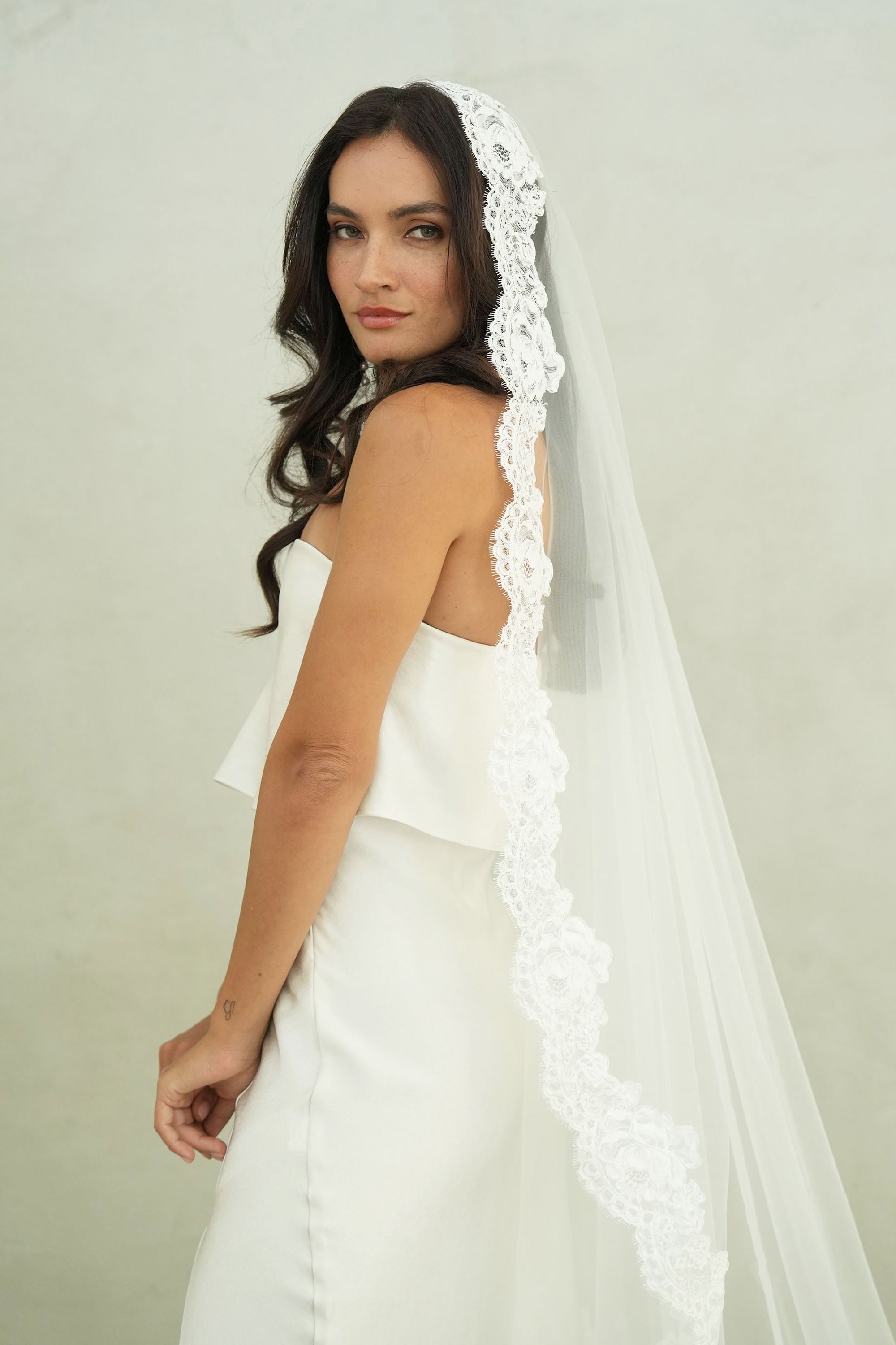 model wears mantilla veil, one-tier lace trim wedding veil