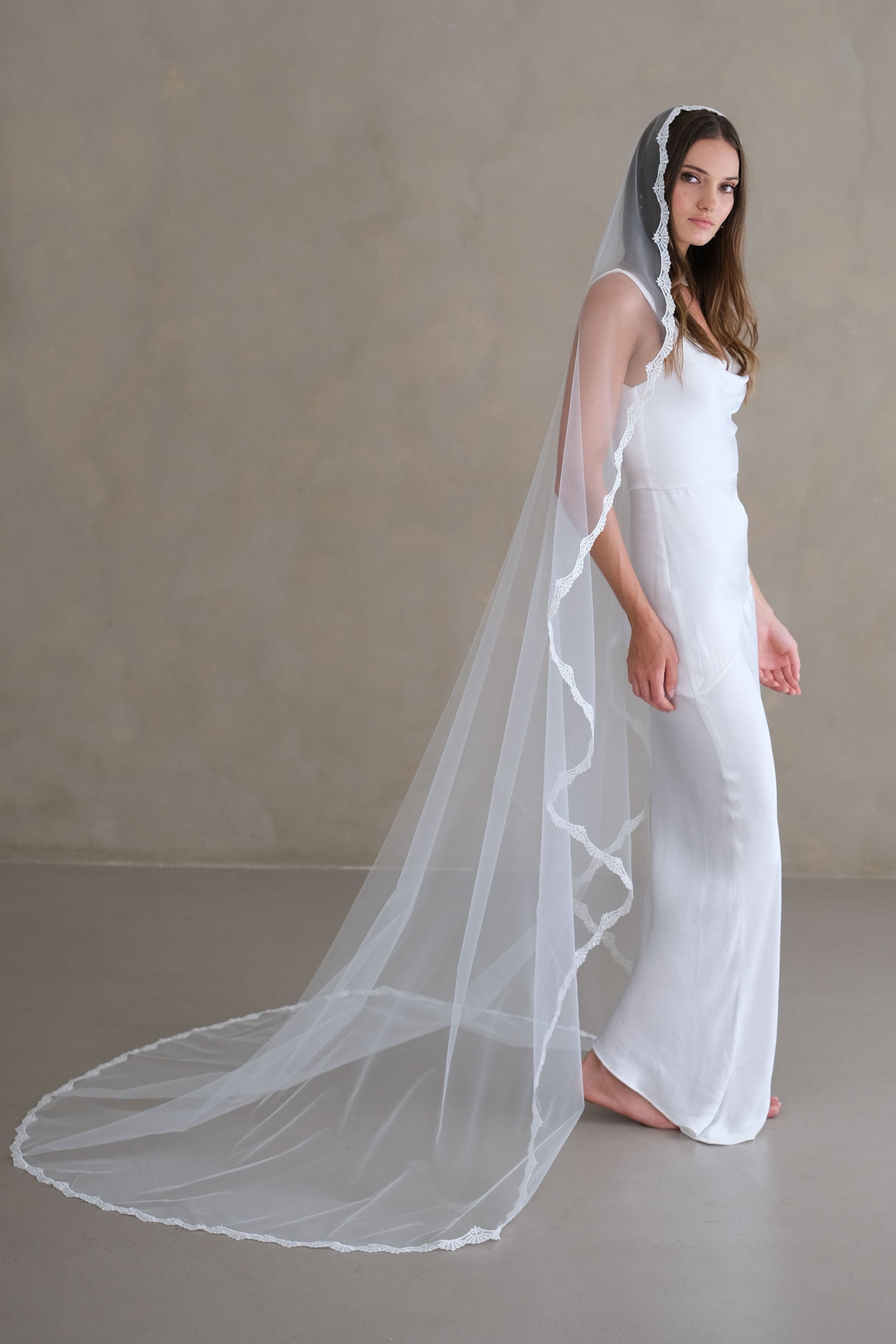 Model wears a lace wedding veil, one-tier veil with lace edge.