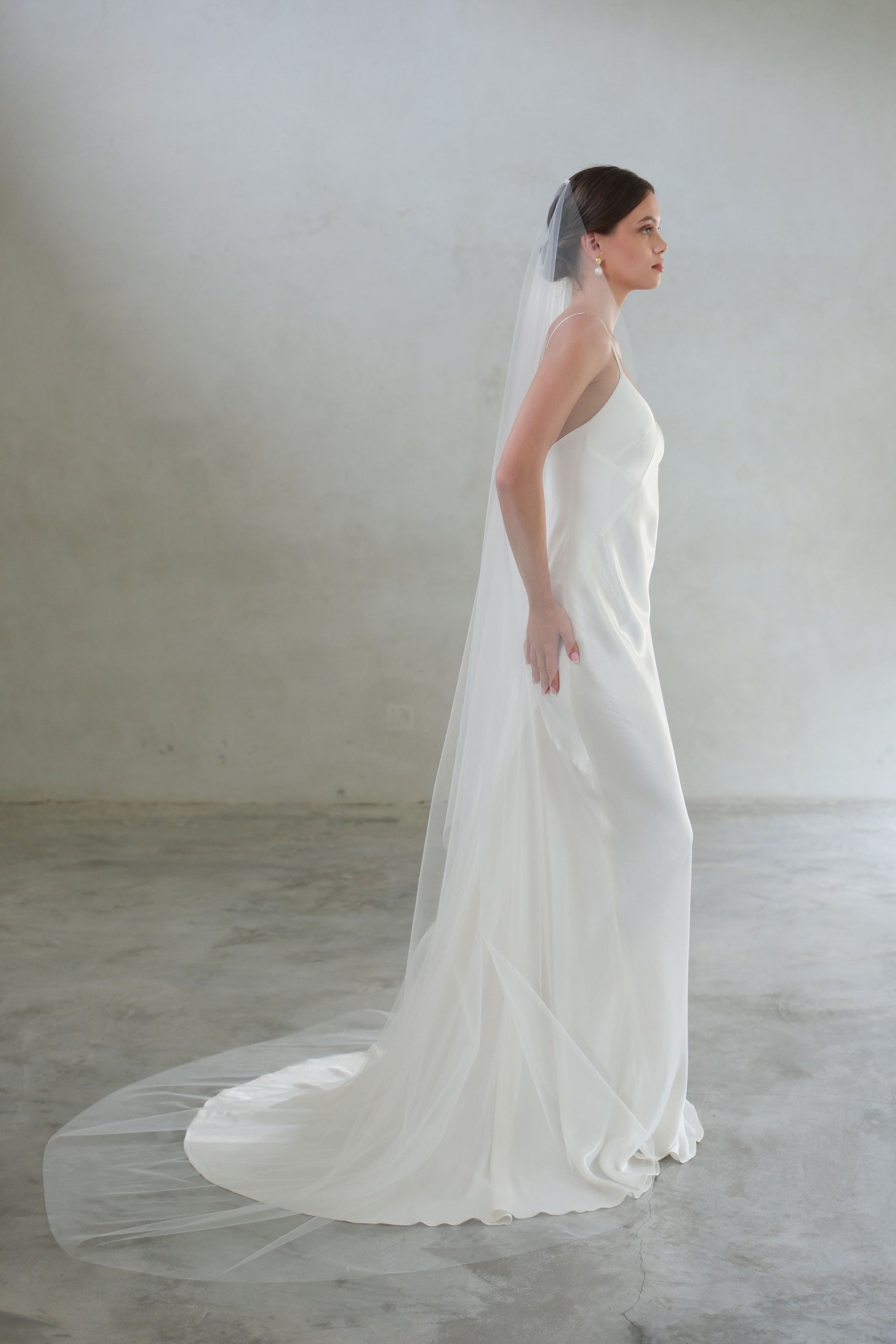 Full length bride in profile wears long, one tier veil in plain tulle