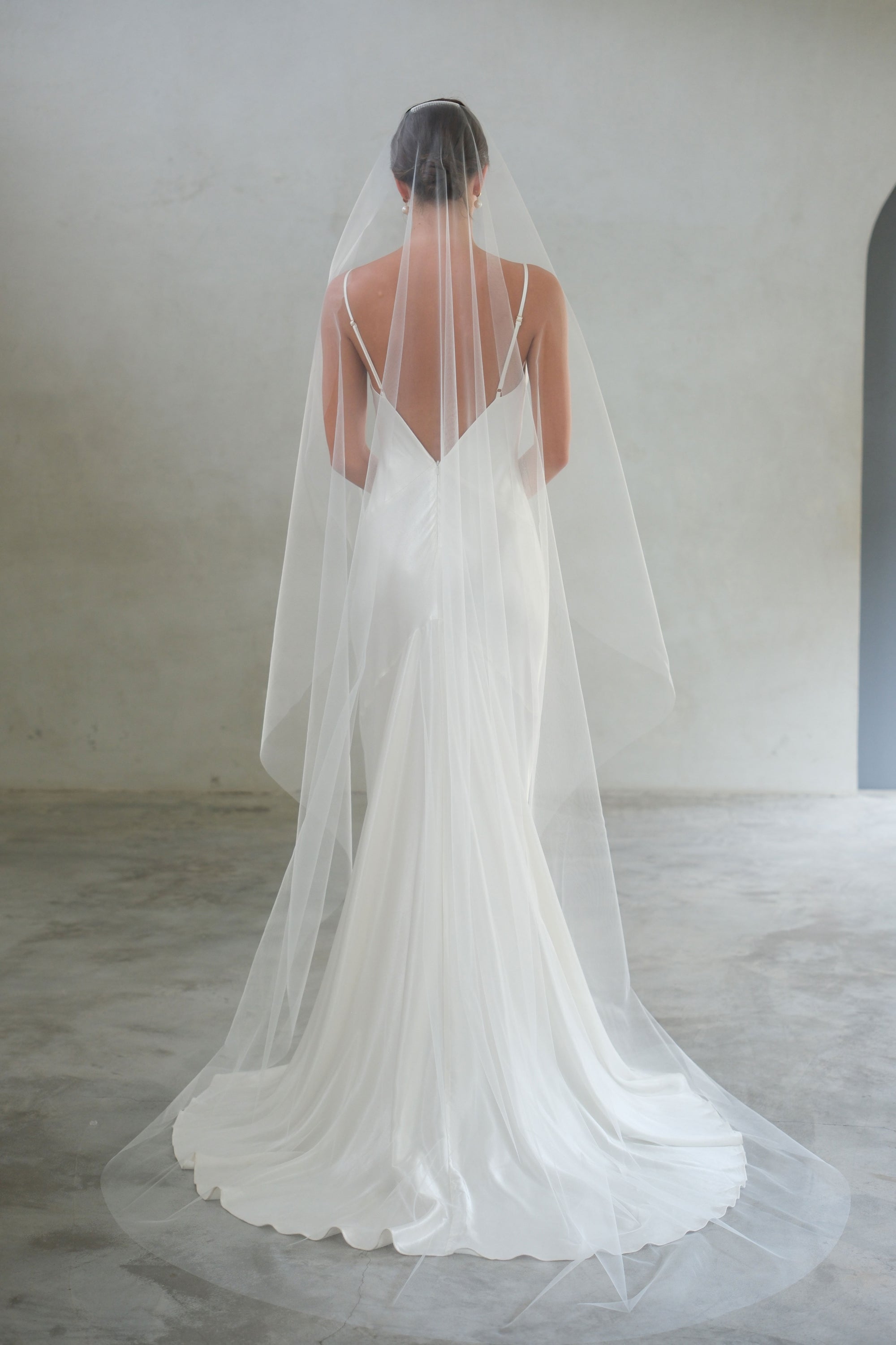 Full length back view showing draping of long minimalist bridal veil