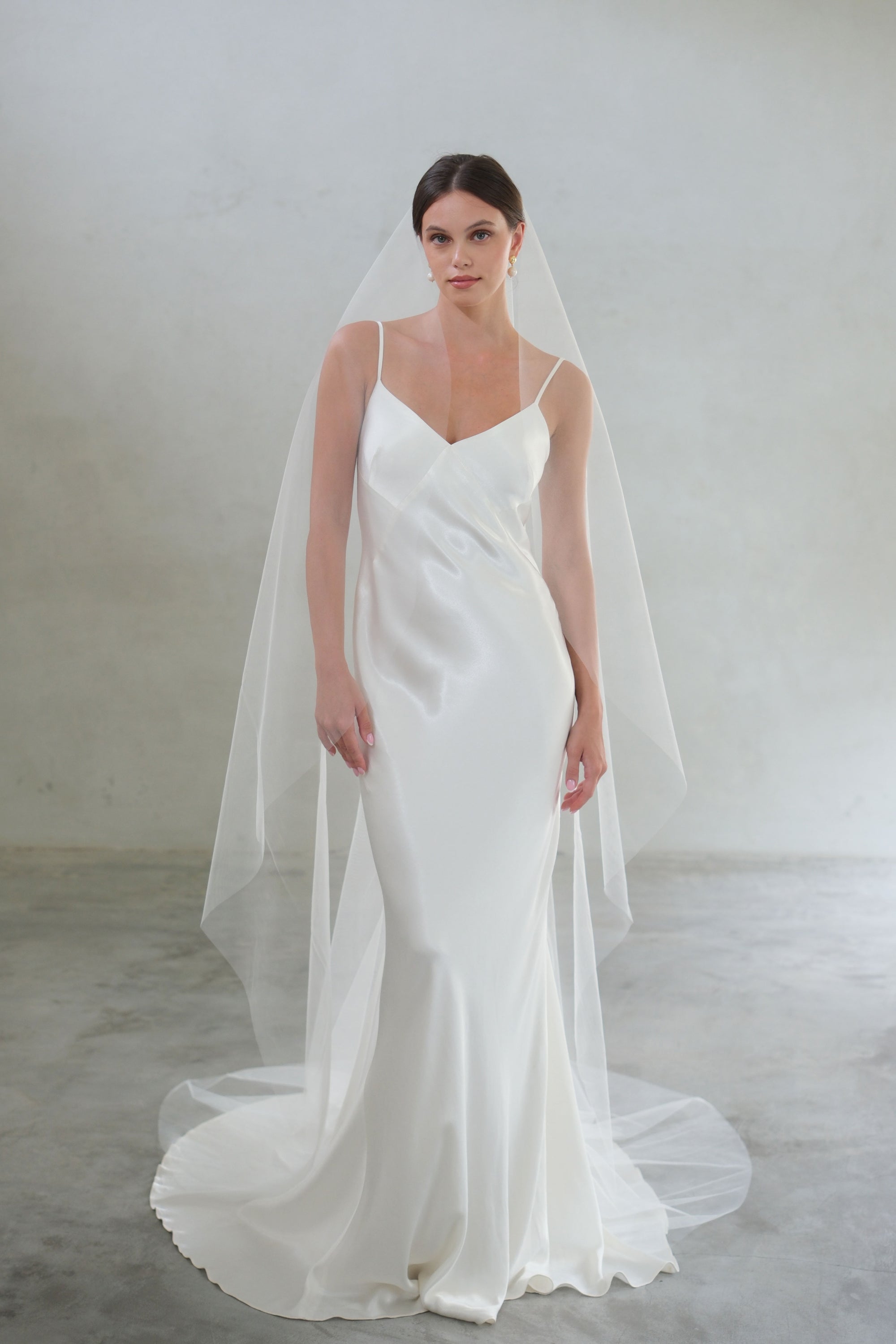 Full length front facing bride wears long, one tier unadorned tulle veil