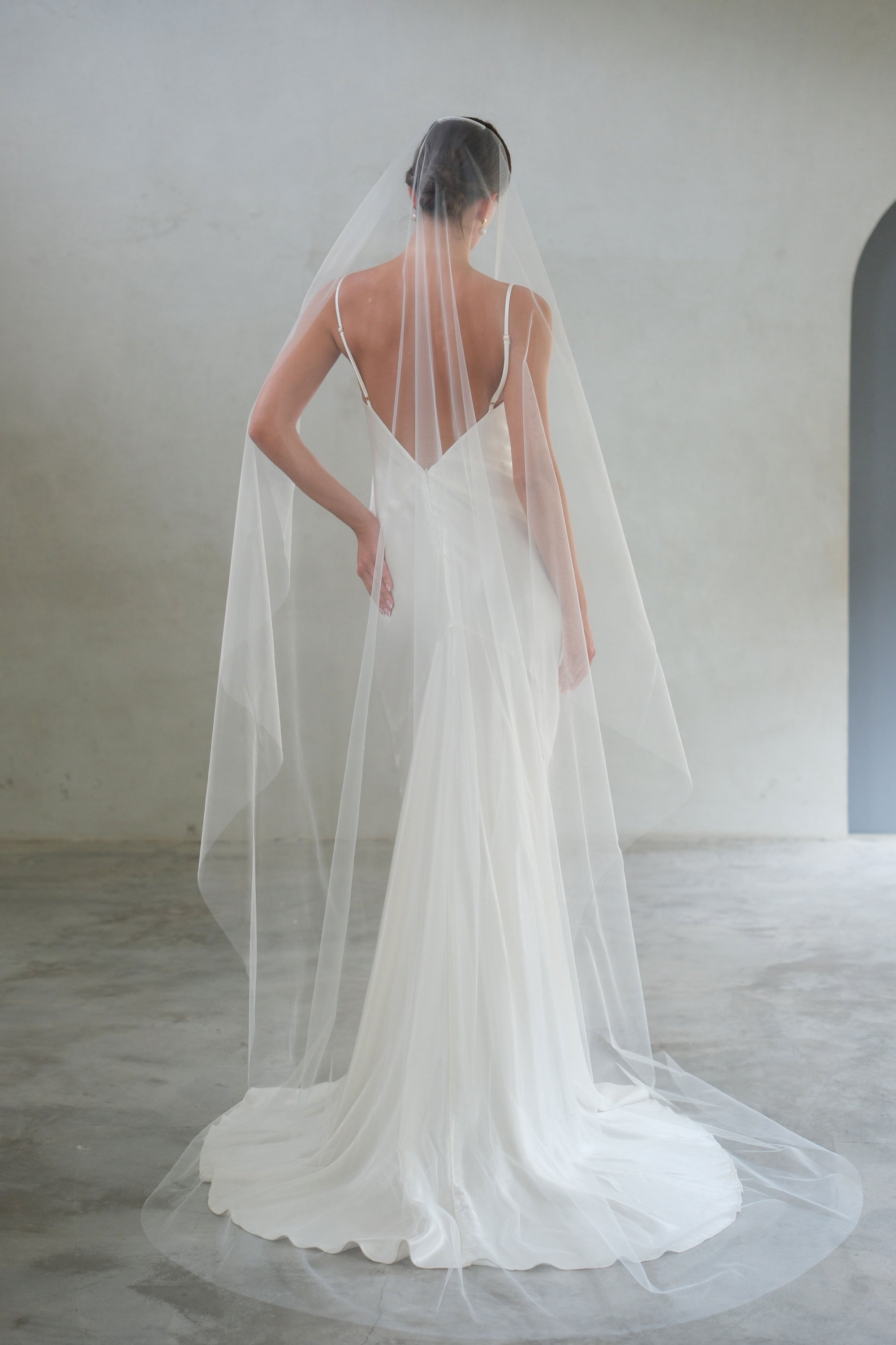 Full length back view showing romantic draping of one tier minimalist tulle bridal veil