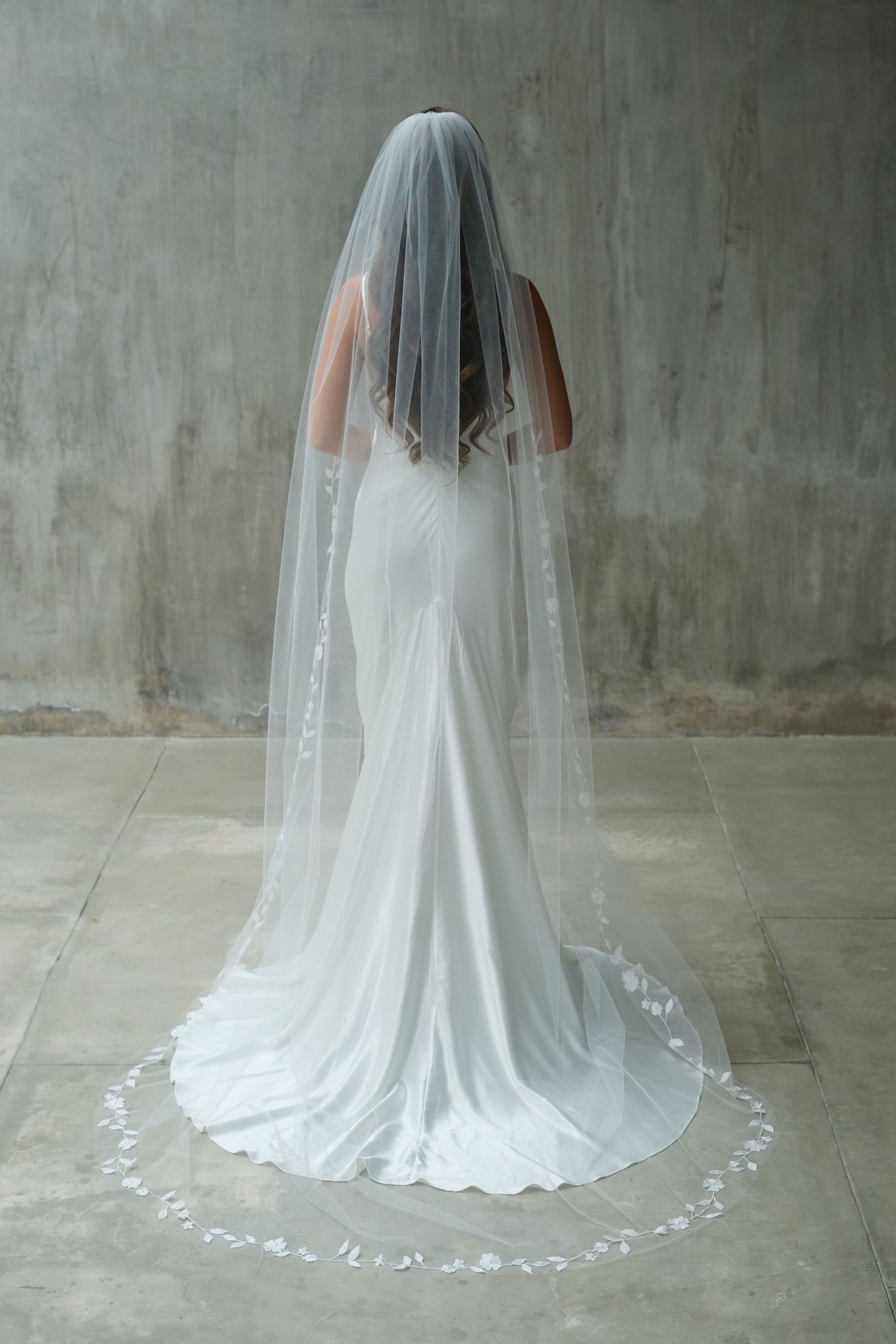 Full length back view of long bridal veil, gathered at the comb and edged with delicate embroidered floral vine